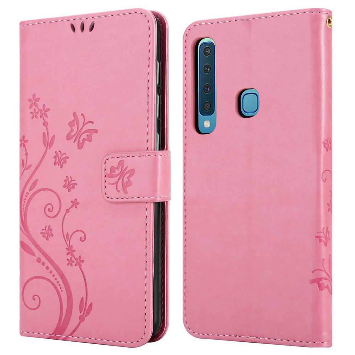 Custodia rosa per telefono con design floreale e farfalle. Aperta e chiusa. I pulsanti del telefono sono visibili.
