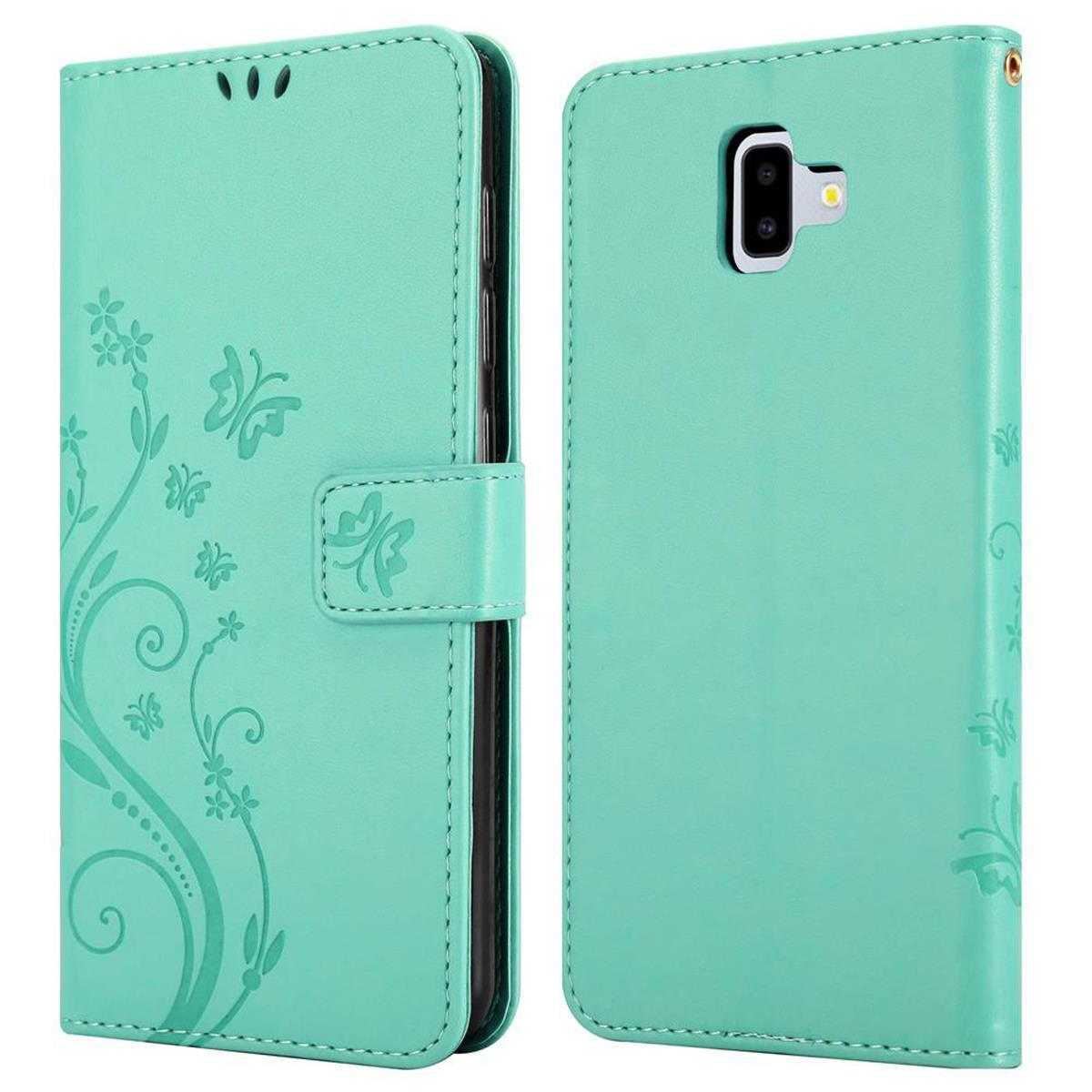 Una custodia per telefono verde acqua con un design floreale sul davanti e un foro per la fotocamera sul retro.