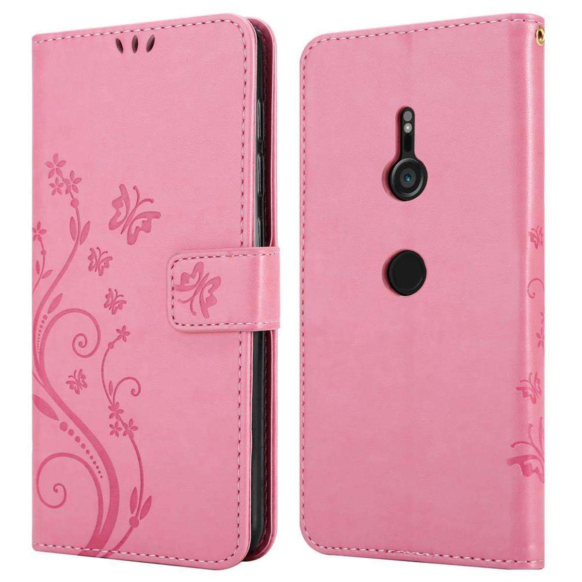 Custodia rosa per telefono. Design floreale sulla cover anteriore. Chiusa con patta. Retro mostra la fotocamera.