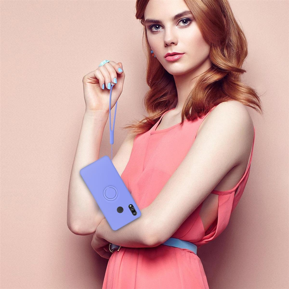 Donna che tiene un telefono viola con un anello per il cinturino da polso, sfondo rosa.