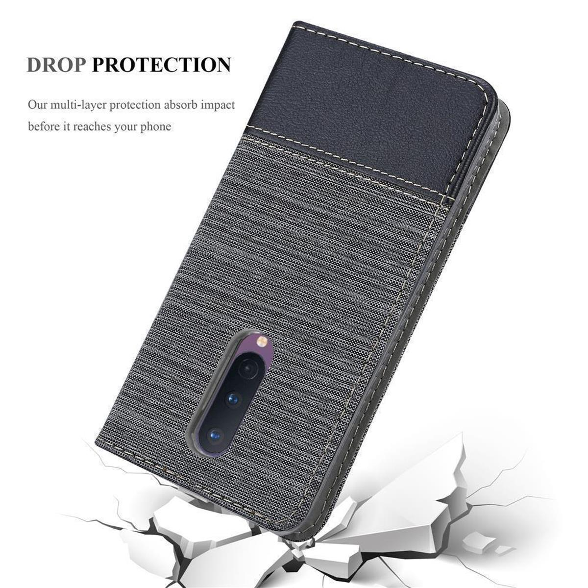 Eine Handyhülle mit schwarzem und grauem Design, liegt auf einer Oberfläche mit Rissen. Text: 'Drop Protection'.