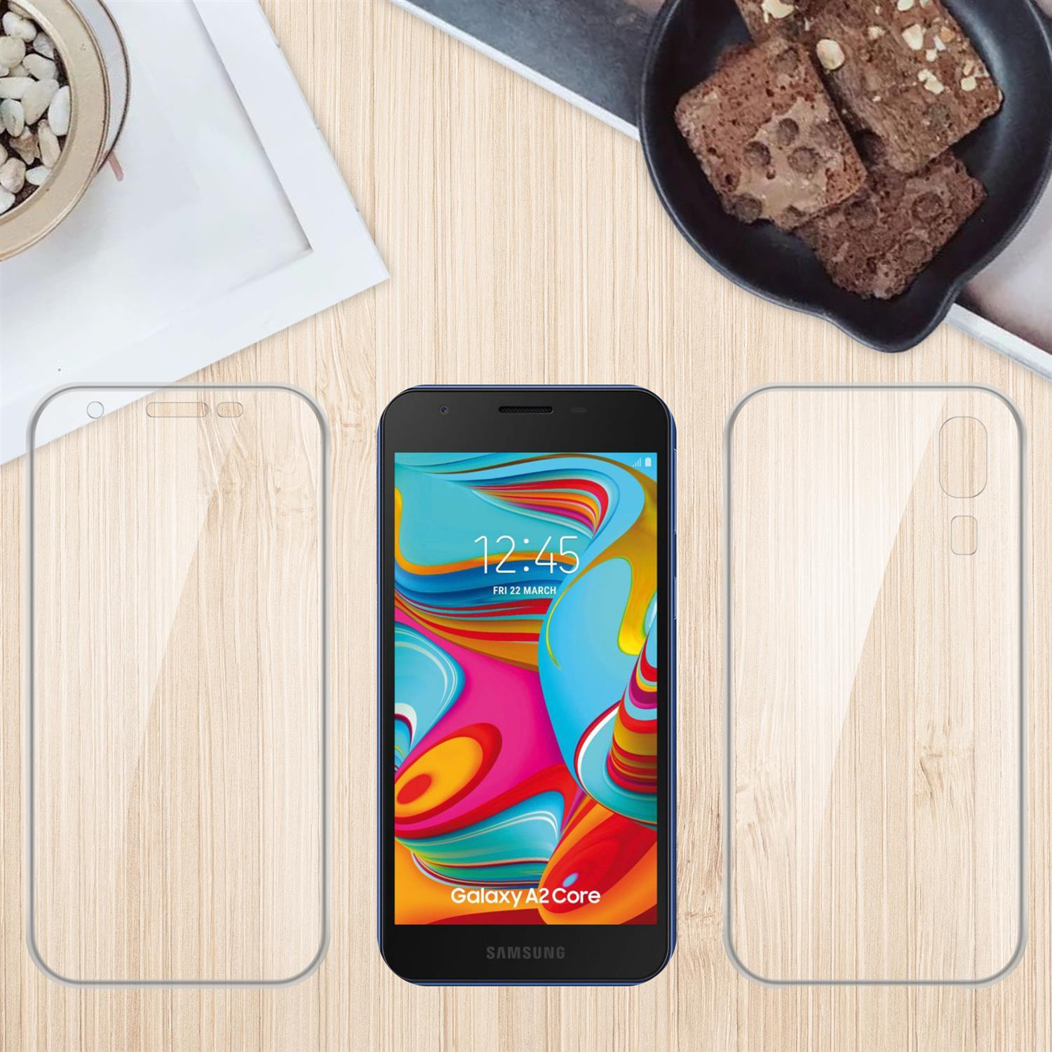 Telefono, protezione schermo e custodia su tavolo di legno con brownies sullo sfondo.