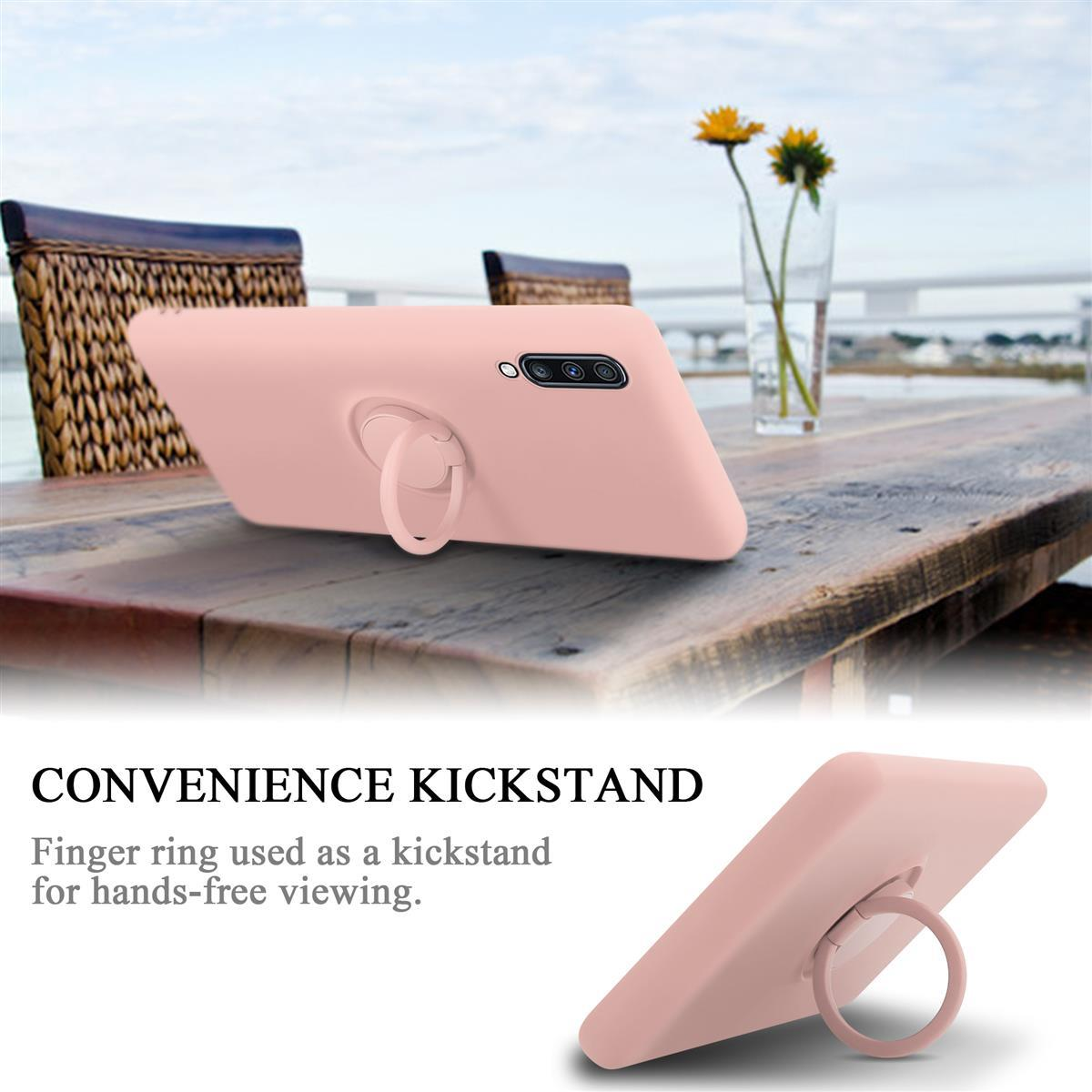 Una custodia per telefono rosa con un porta anelli, appoggiata su un tavolo. Lo sfondo ha un lago e degli alberi. Il testo dice cavalletto.