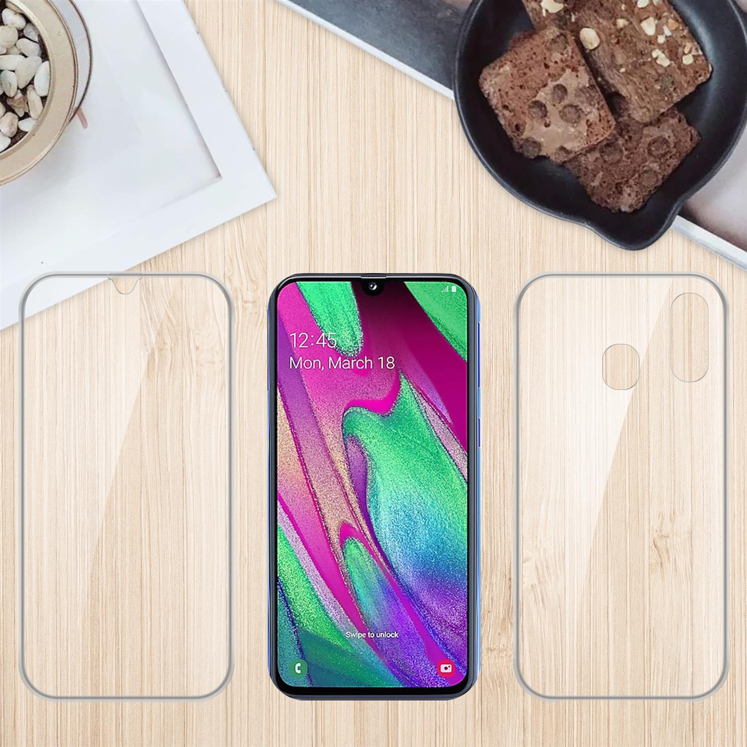 Telefon mit Displayschutz und Schutzhülle, auf Holztisch, Brownies im Hintergrund.