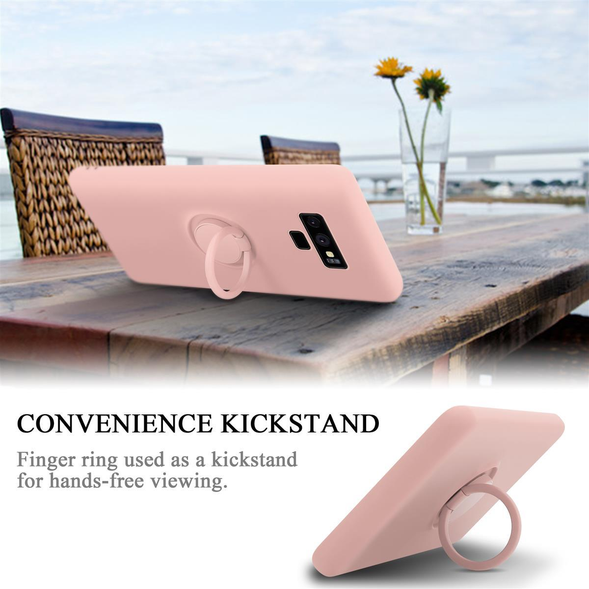 Custodia rosa con anello e testo 'Convenience Kickstand'. Un tavolo di legno sullo sfondo.