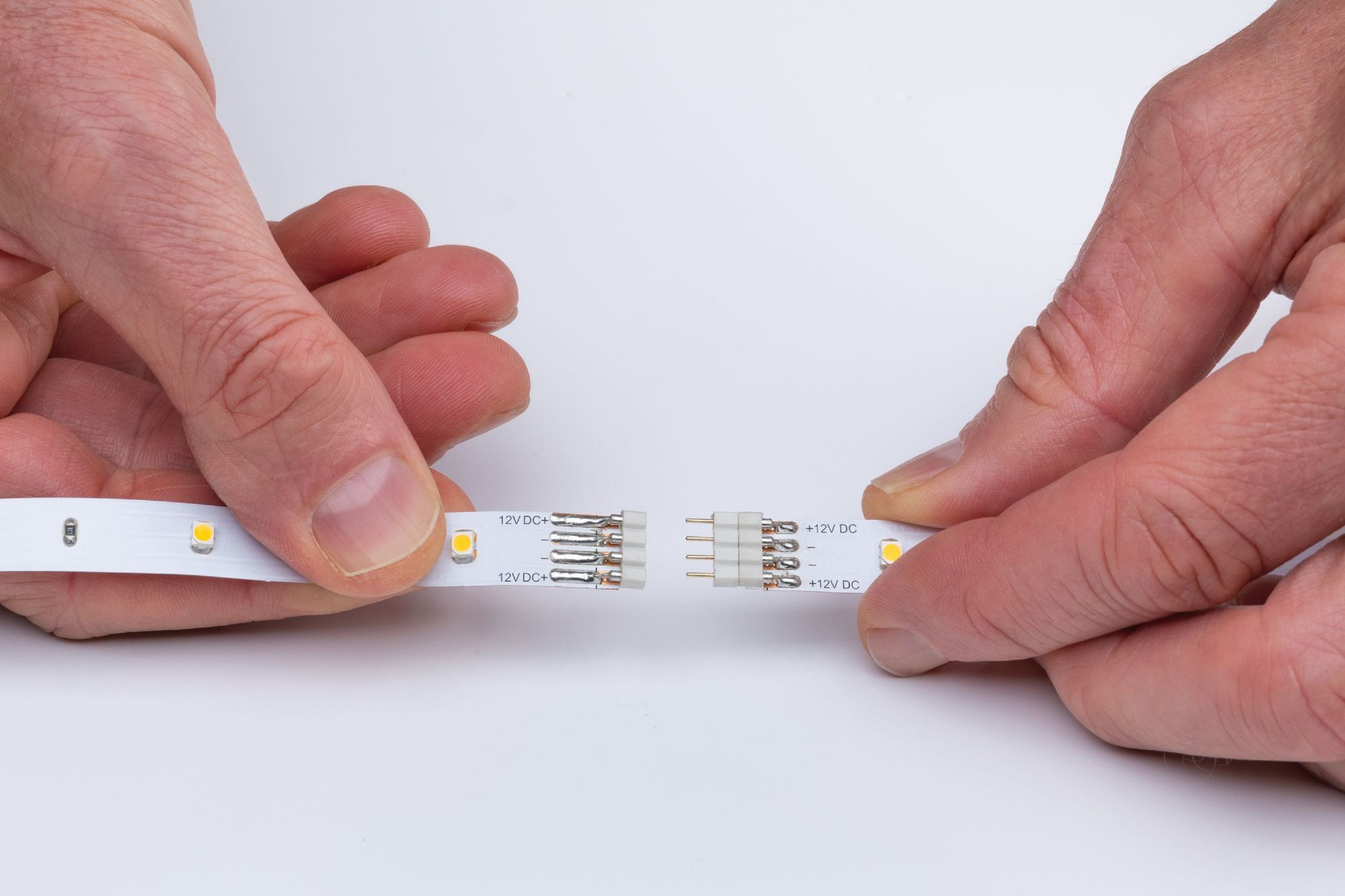 Hände verbinden LED-Streifen, zeigen die Anschlüsse.