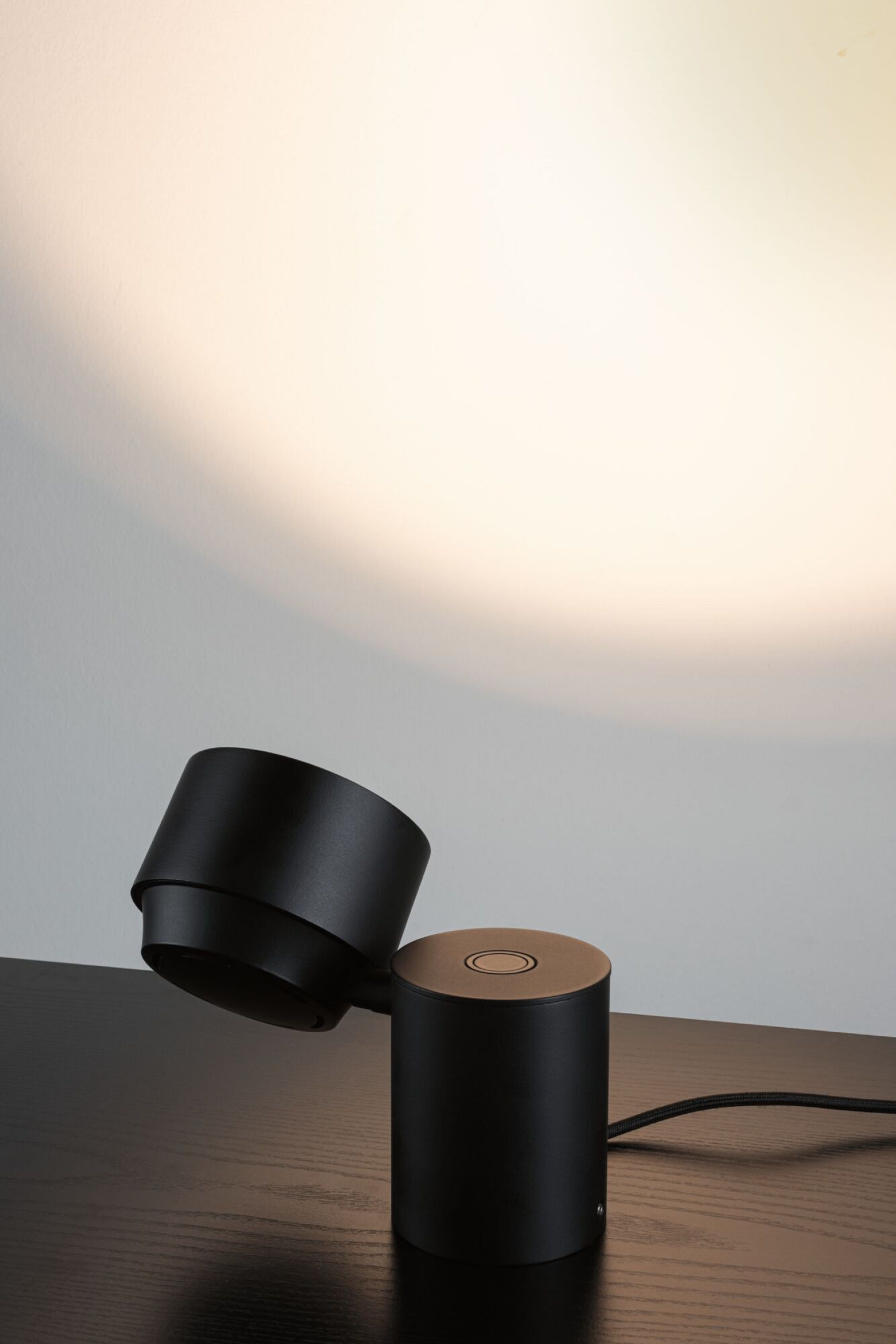 Schwarze Lampe auf einem schwarzen Tisch, Licht scheint auf weißen Hintergrund.