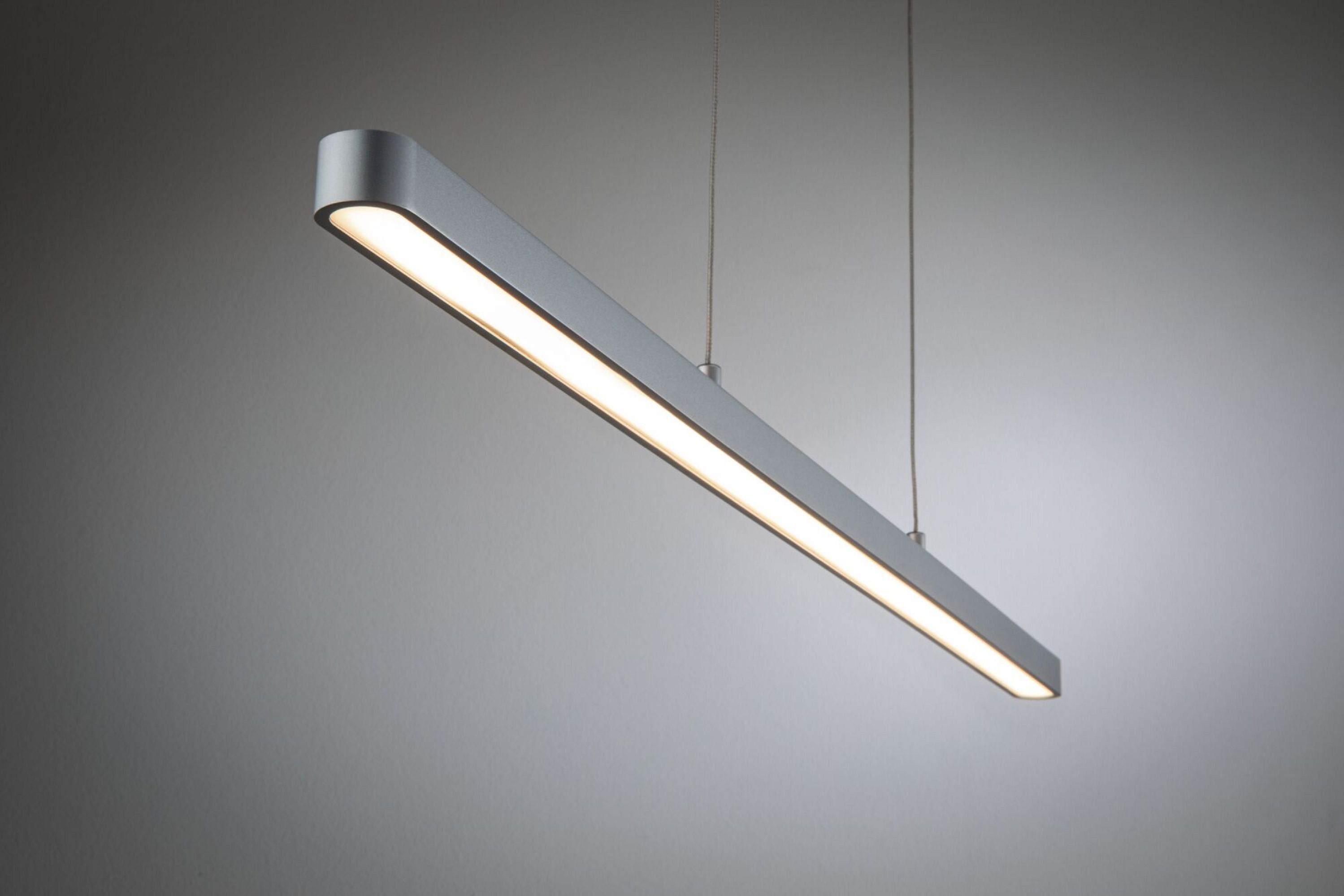 Luminaire argenté, long, rectangulaire, suspendu au plafond, émettant une lumière blanche.