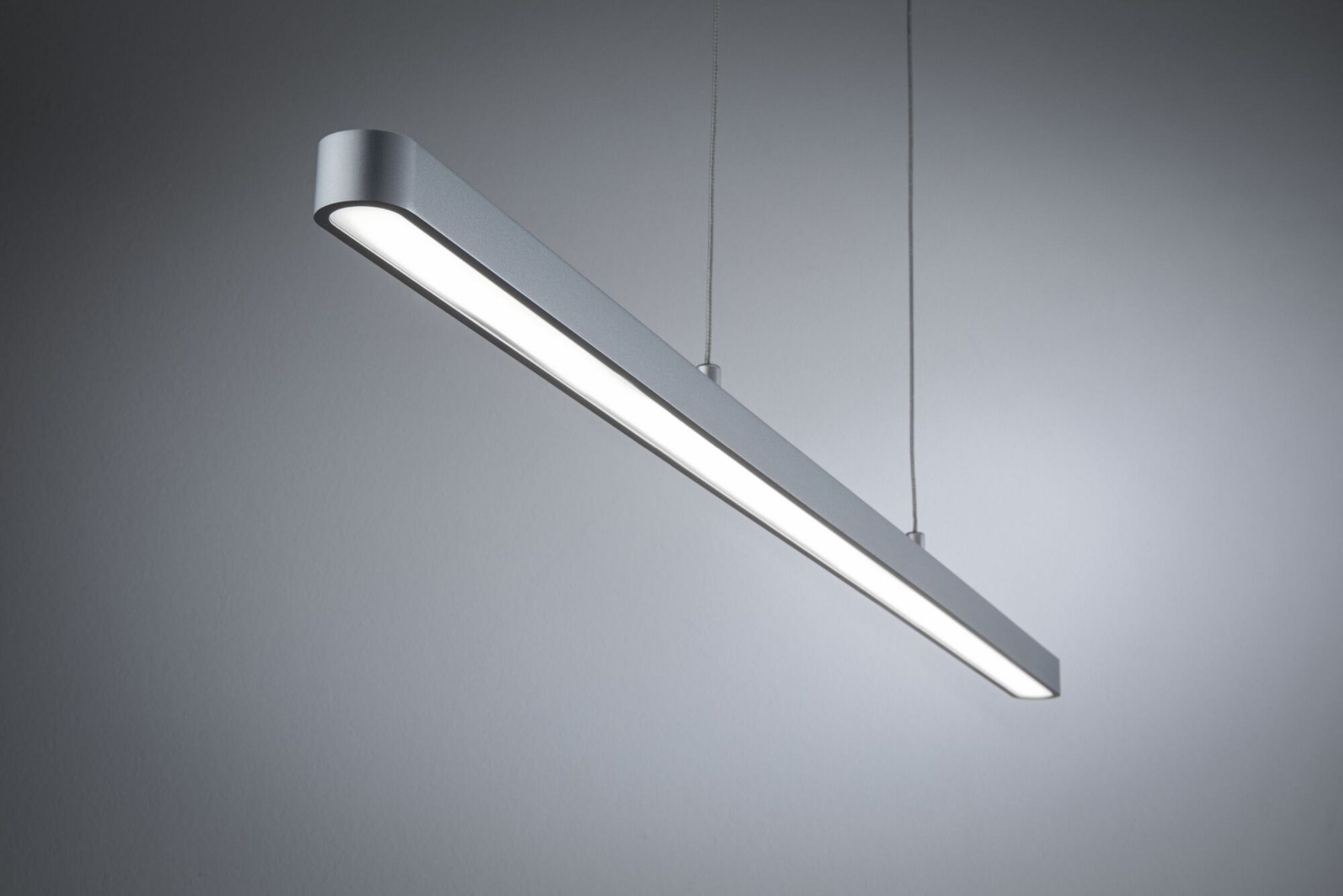 Apparecchio di illuminazione a LED rettangolare argentato appeso a fili. La luce è accesa, emettendo un bagliore.