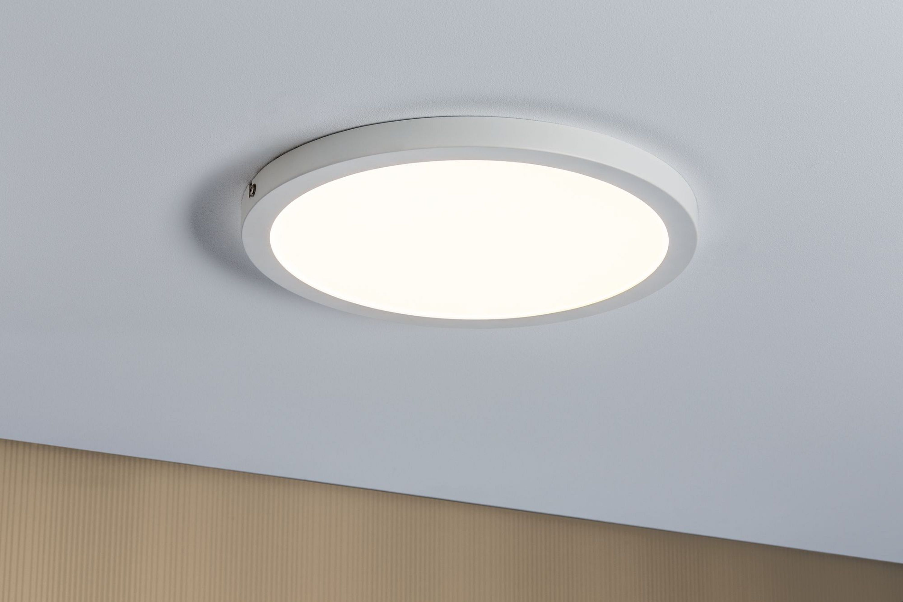 Una plafoniera circolare bianca, che illumina il soffitto bianco. La luce è centrata.