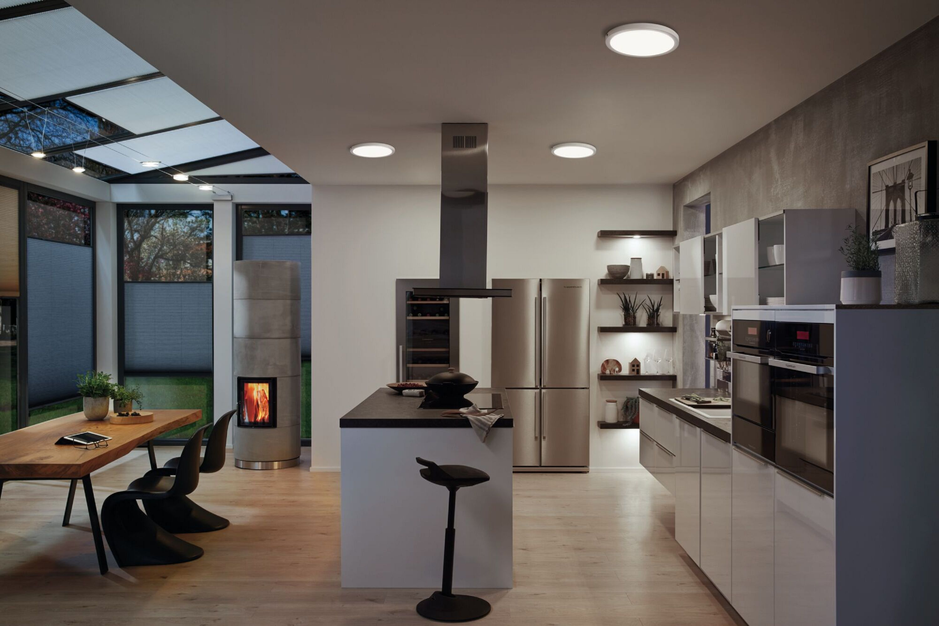 Una cucina con mobili bianchi, isola e luci a soffitto, con finestra e camino.