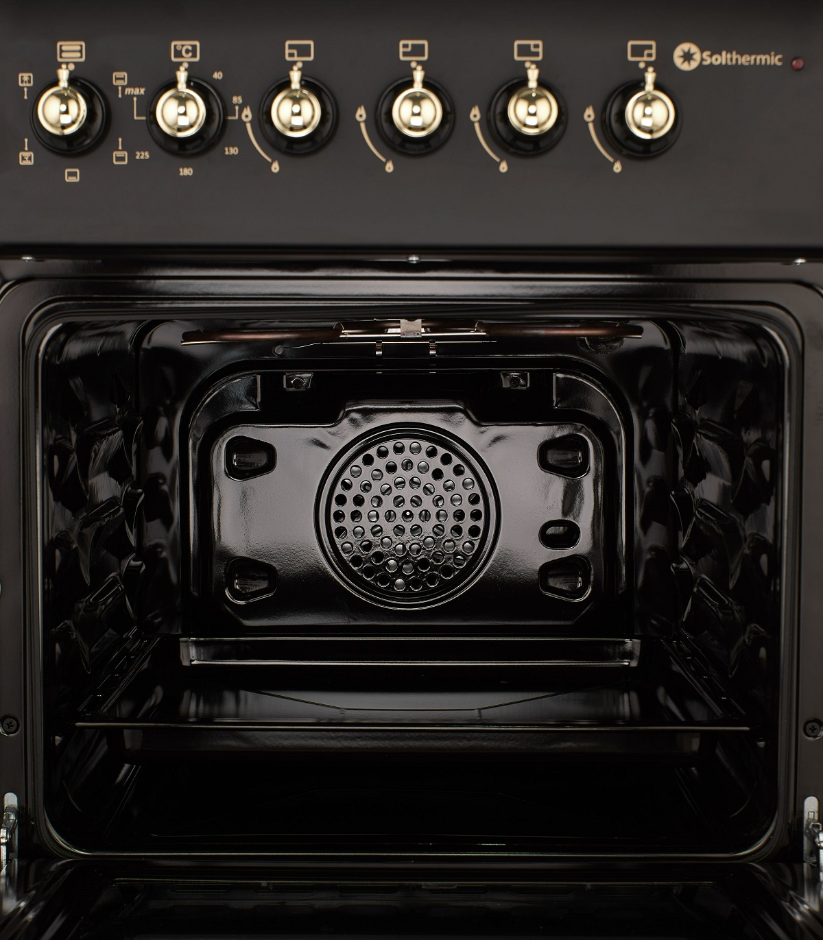 Interior del horno, negro con elementos calefactores y panel de control. Perillas y ajustes de temperatura visibles.