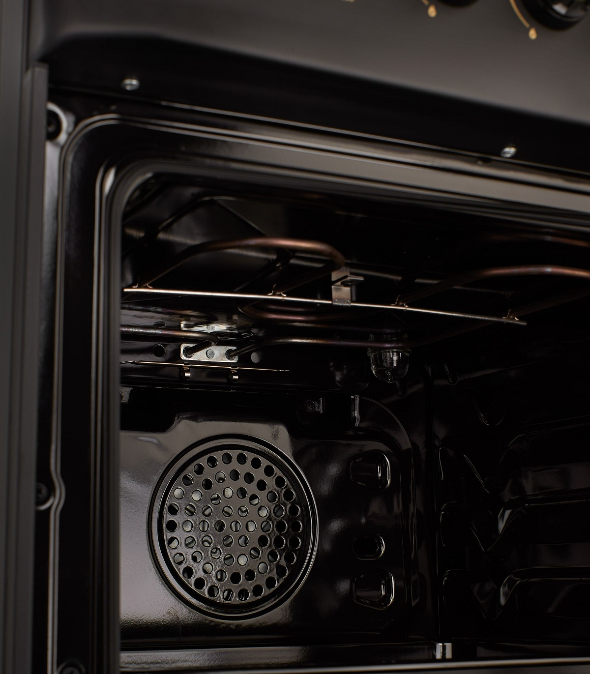 Primer plano del interior de un horno, mostrando el elemento calefactor y el ventilador, acabado oscuro y brillante.