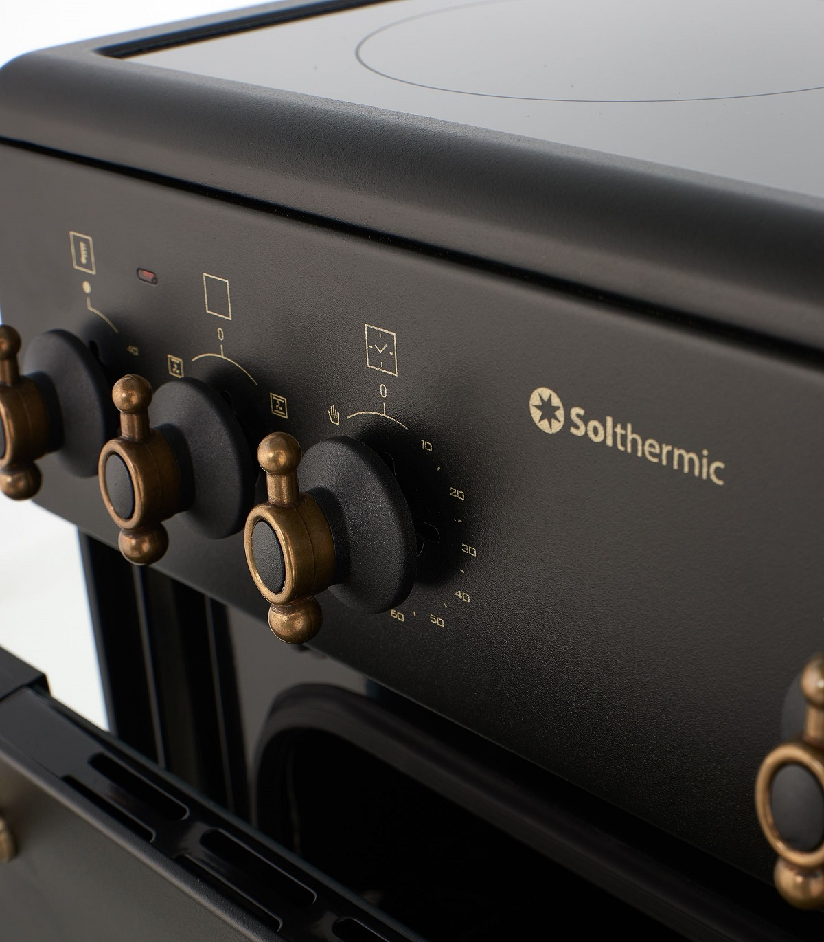 Primer plano de un horno negro con perillas doradas y el logotipo 'Solthermic'.