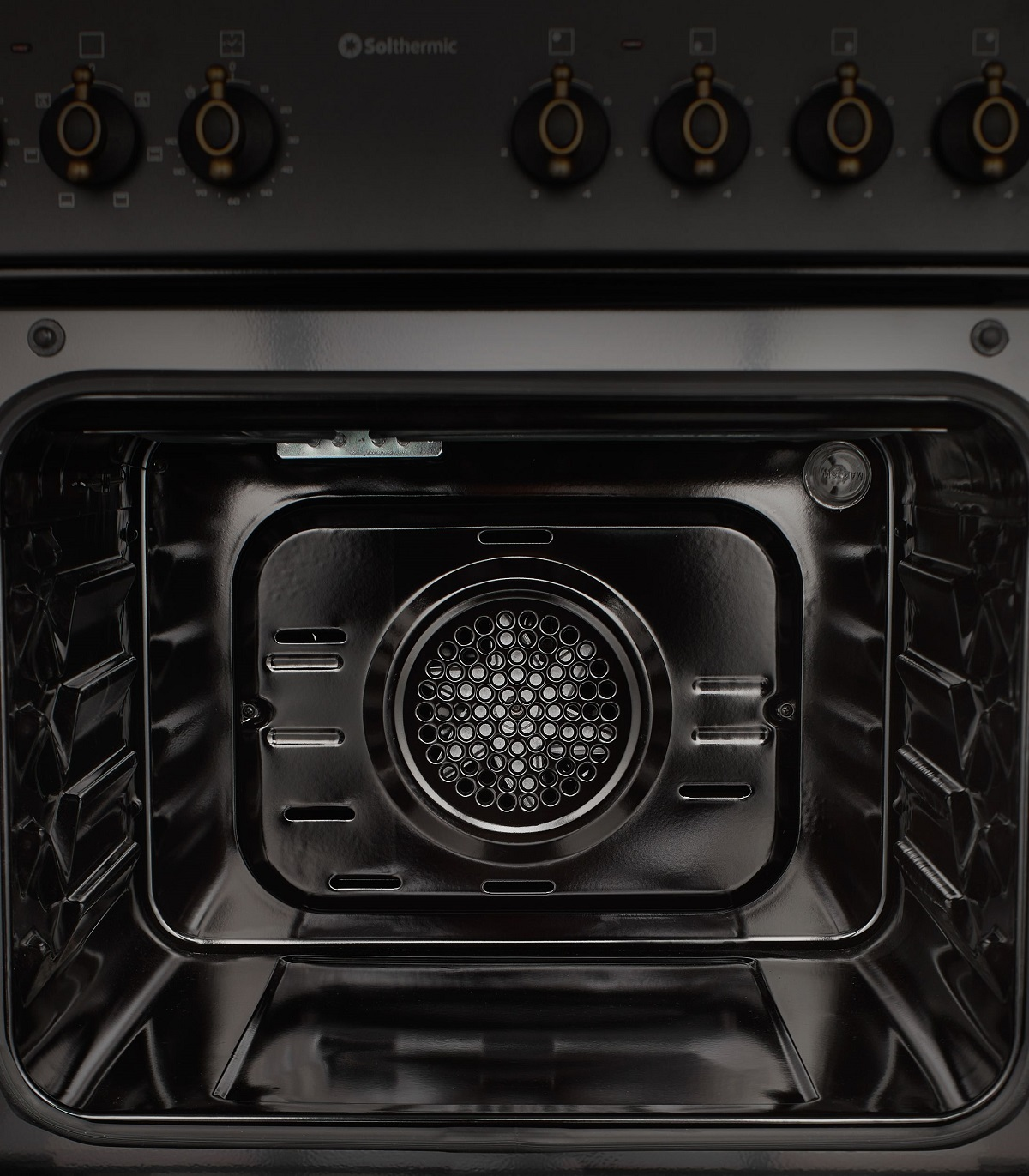 Interior de un horno negro, con una parrilla de metal y una fuente de calor metálica.