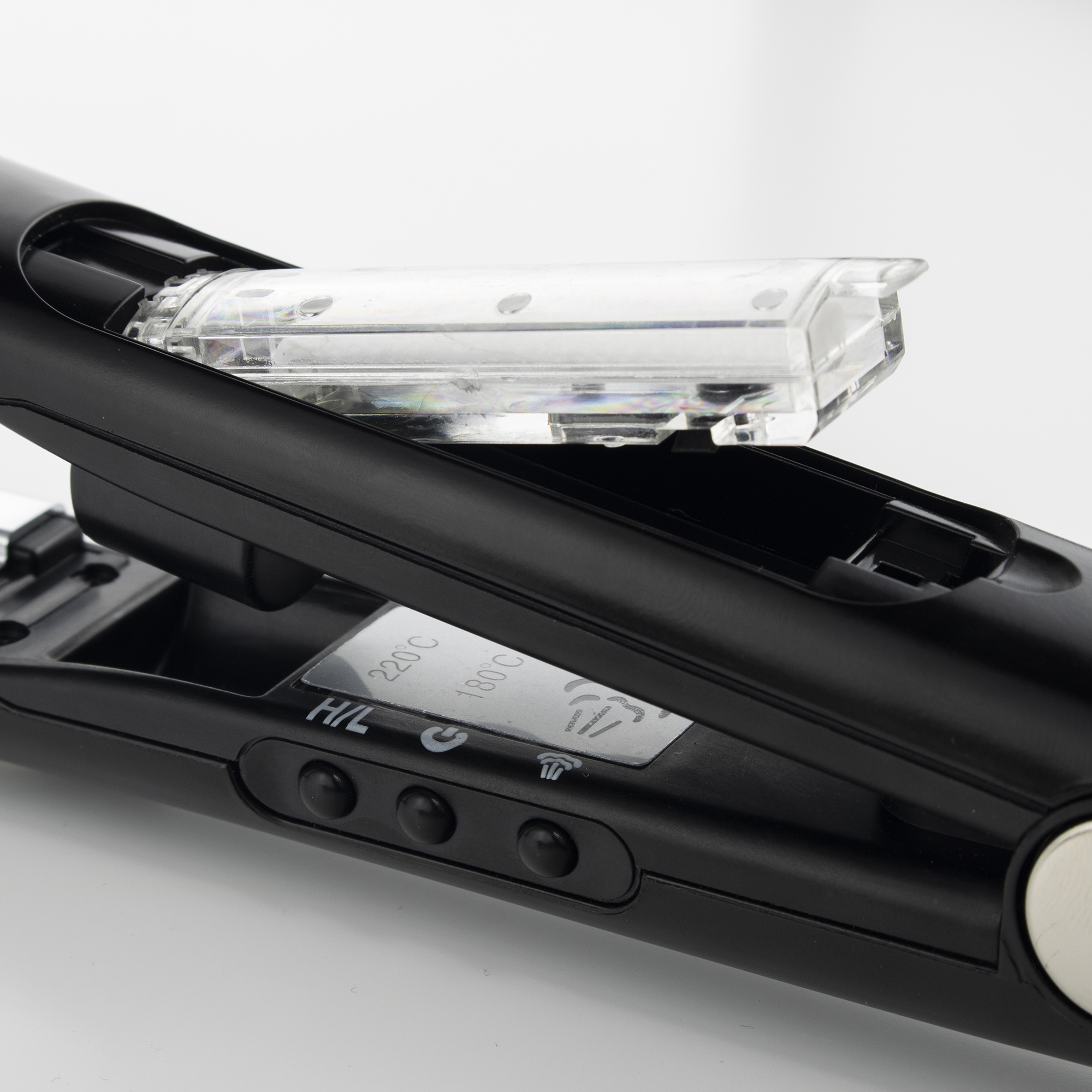 Primer plano de una plancha de pelo negra con cubierta de plástico transparente. Se ven botones e indicadores de temperatura.