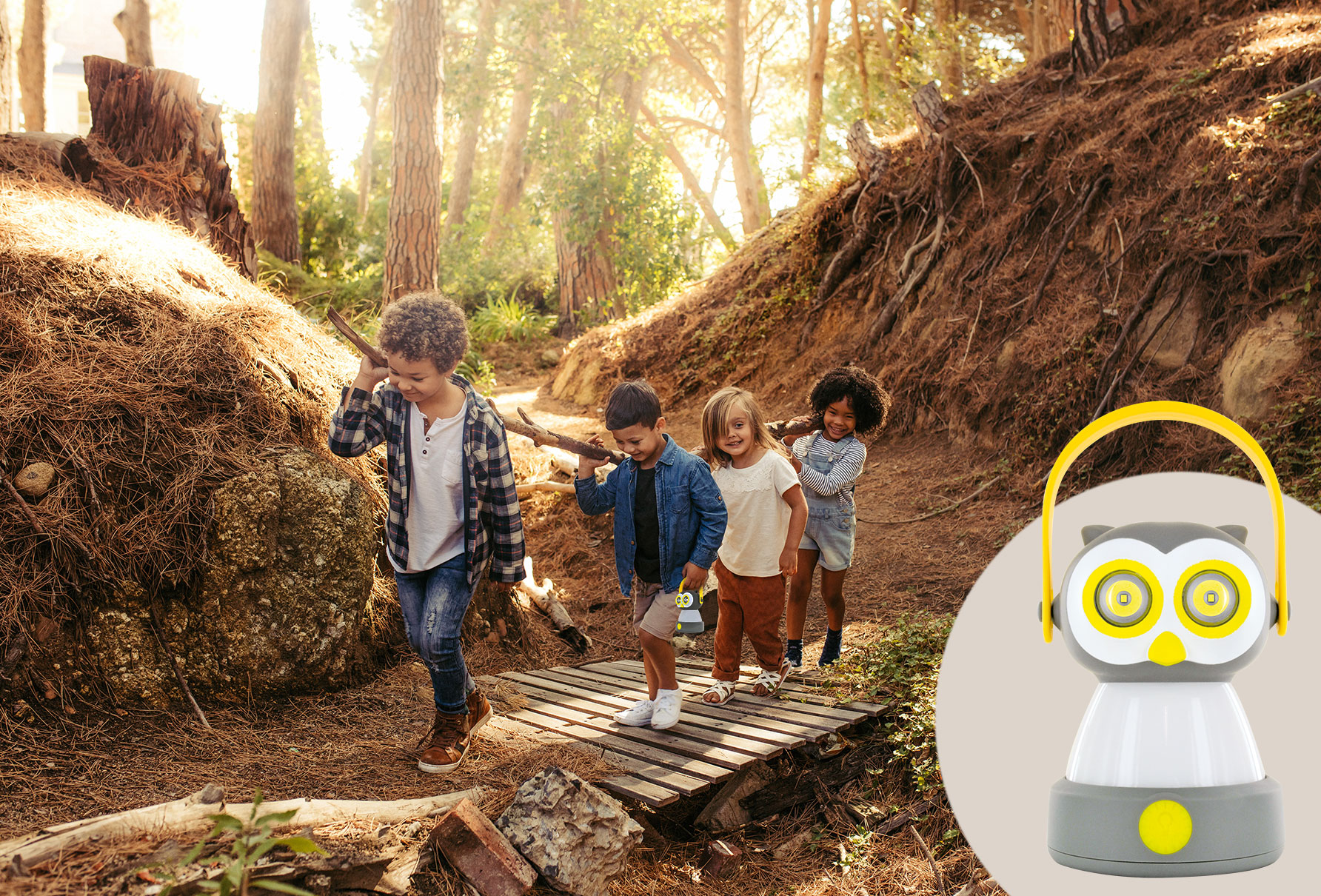 Kinder gehen auf einer Holzbrücke in einem Wald. Eulenlaterne rechts.