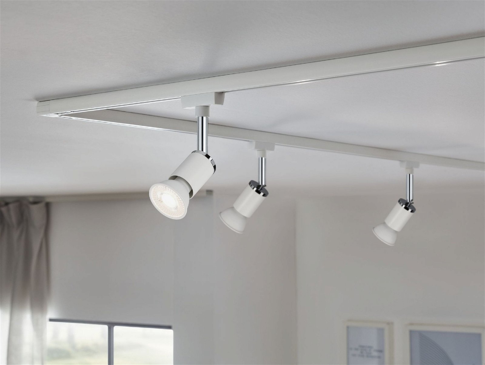 Trzy białe lampy punktowe na białym torze. Światła skierowane są w dół w stronę widza.