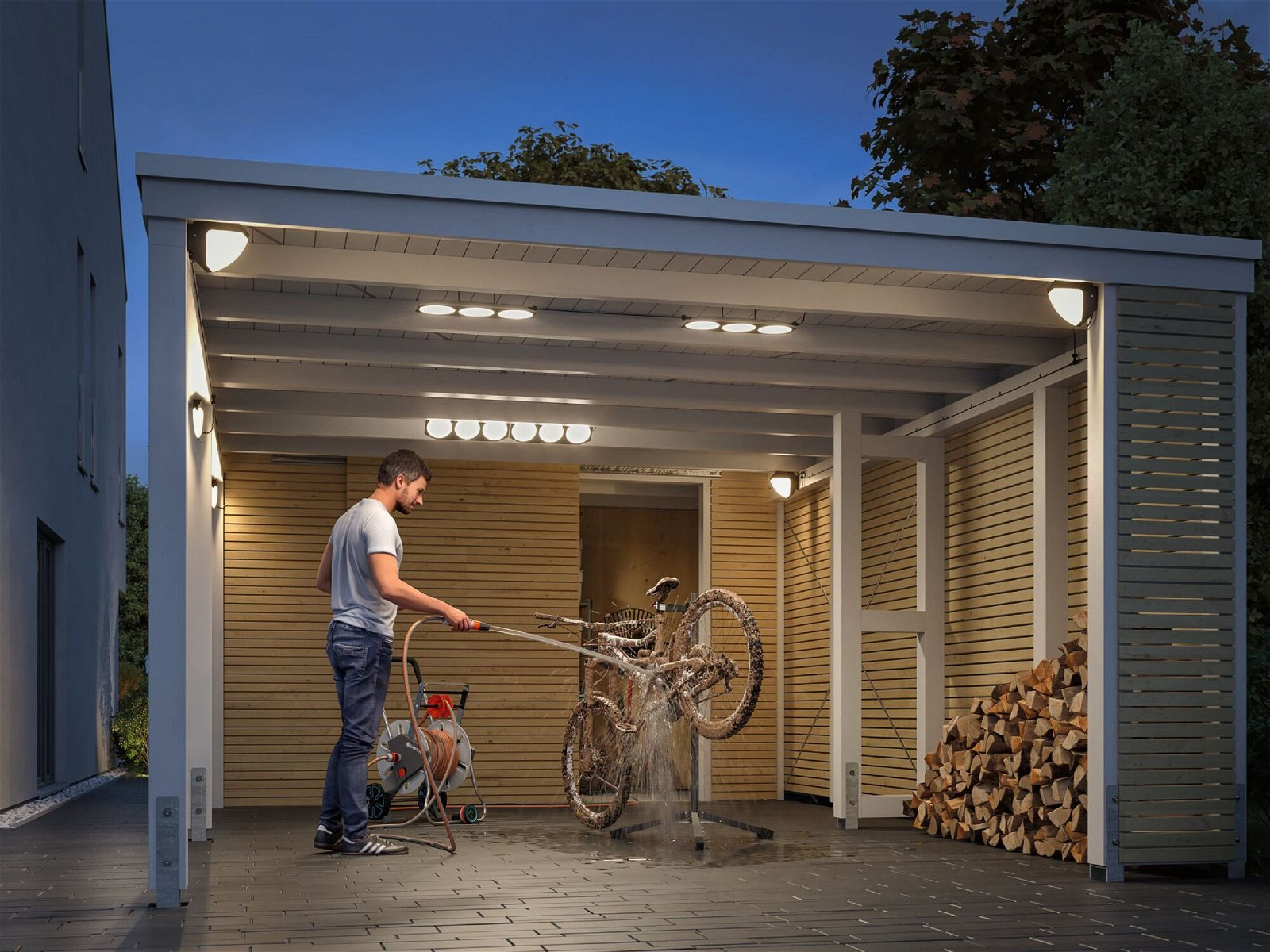 Ein Mann wäscht nachts ein Fahrrad in einer Garage unter künstlichem Licht.