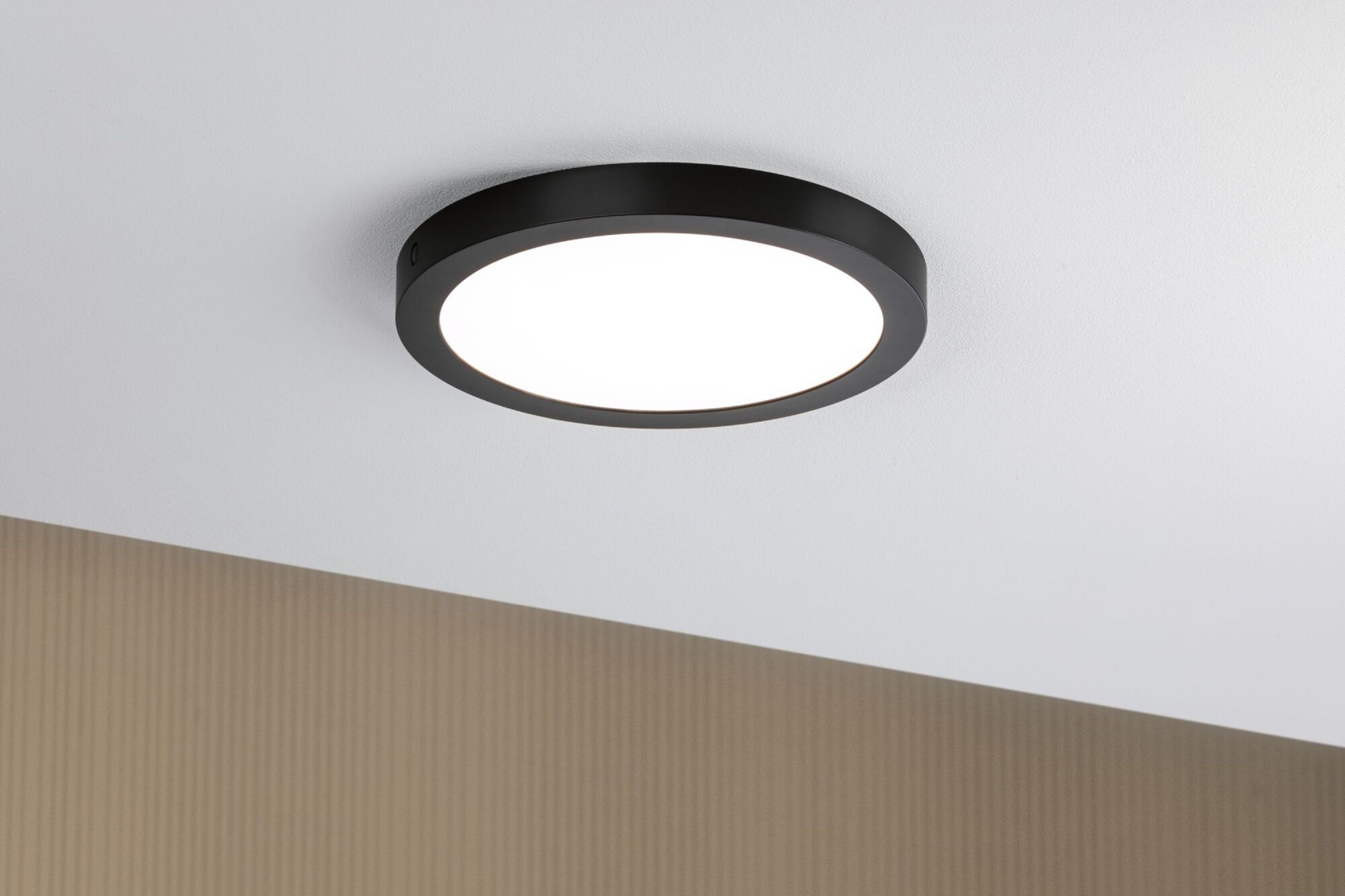 Eine schwarze, kreisförmige Deckenleuchte mit hellem, weißem Licht, das nach unten scheint.