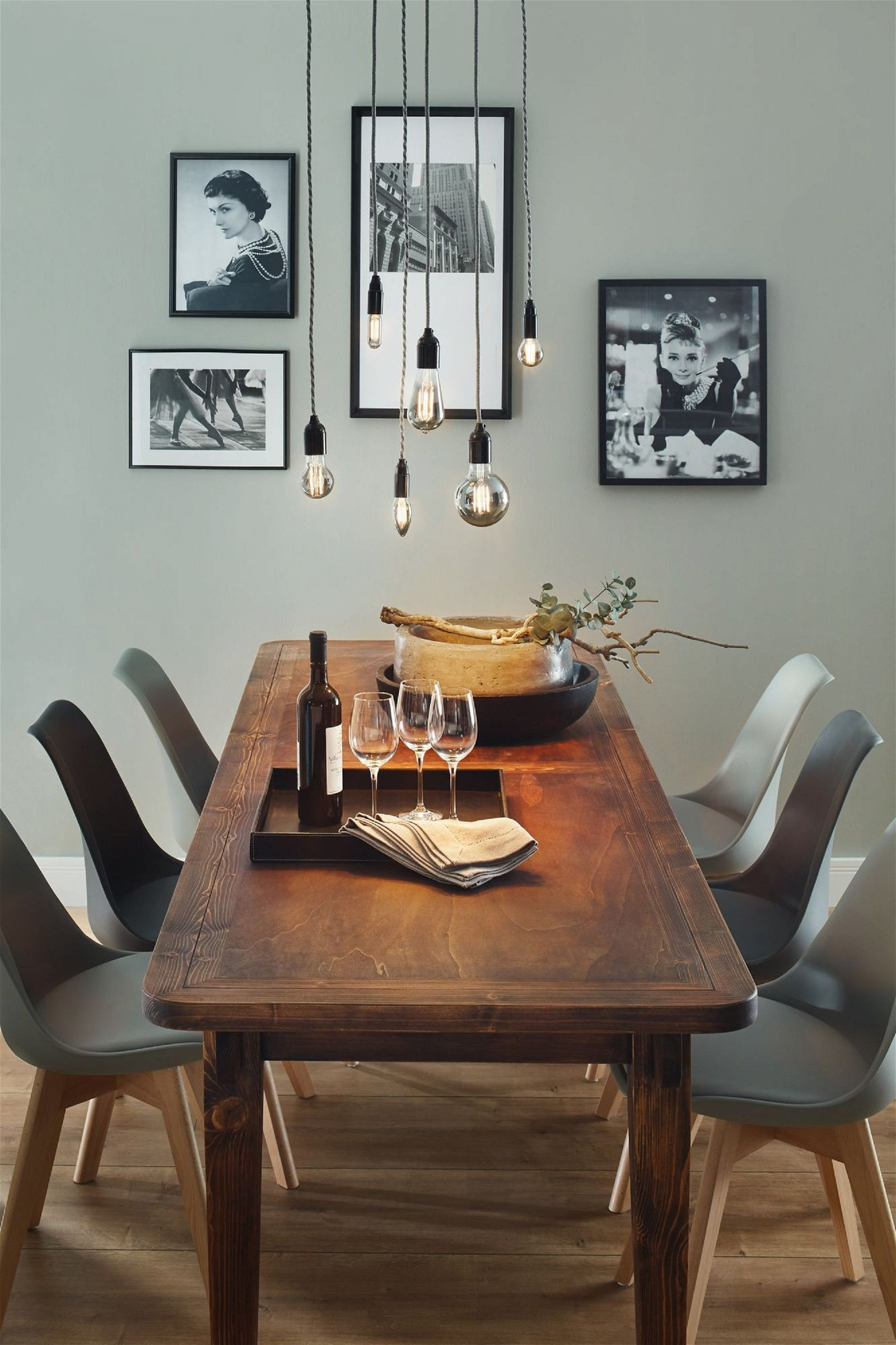 Ein Esszimmer mit Holztisch, Stühlen und Hängelampen.