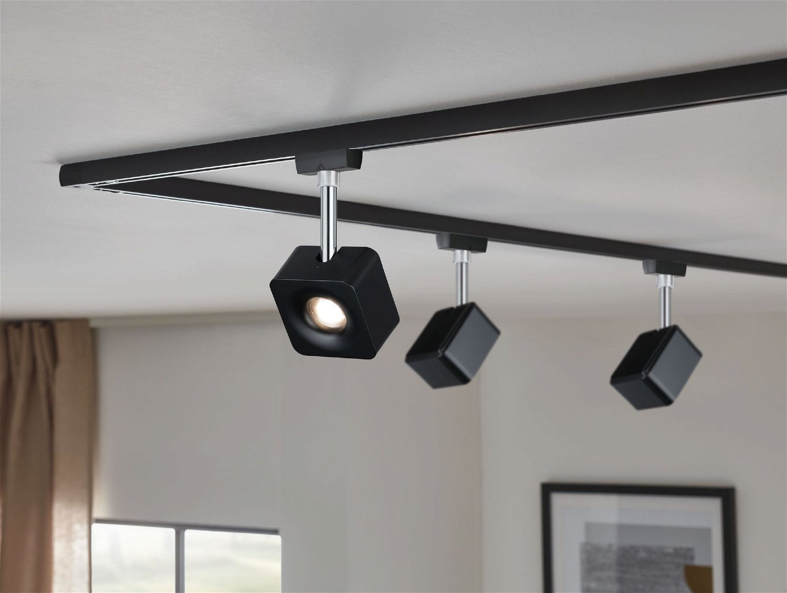 Drei schwarze Strahler an schwarzer Schiene, weiße Decke, moderner Stil.