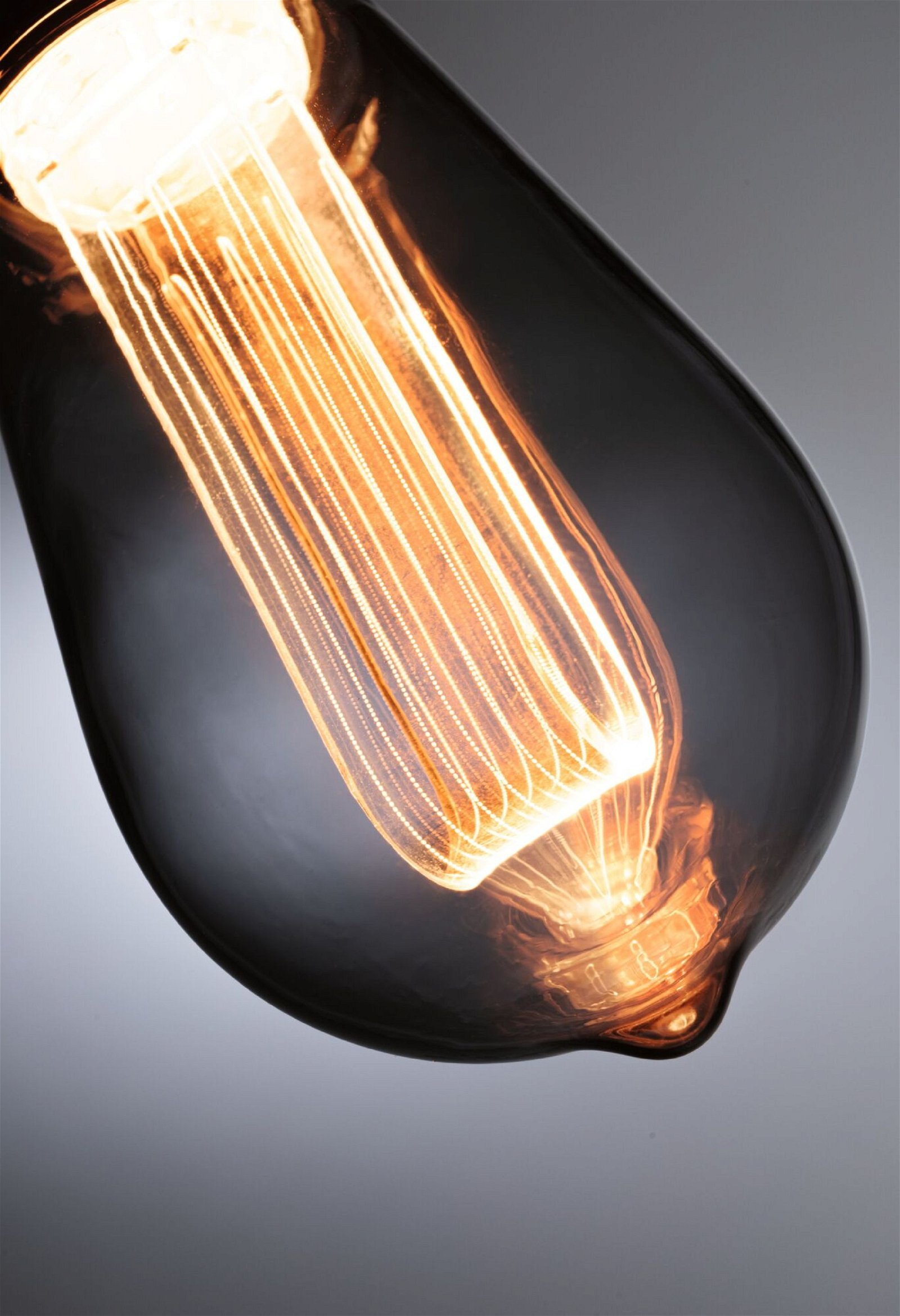 Eine leuchtende Glühbirne im Edison-Stil mit dunklem Glaskolben.