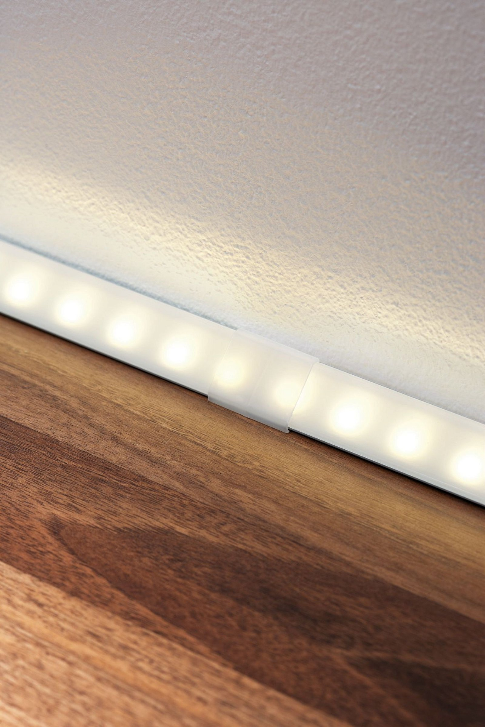 Listwa LED zamontowana na drewnianej powierzchni przy białej ścianie.