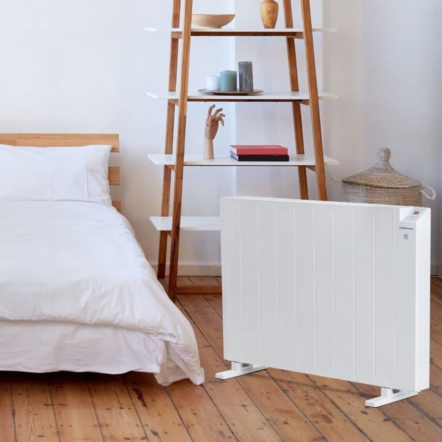 Calentador eléctrico blanco en un dormitorio. El calentador está frente a una cama y estantes.