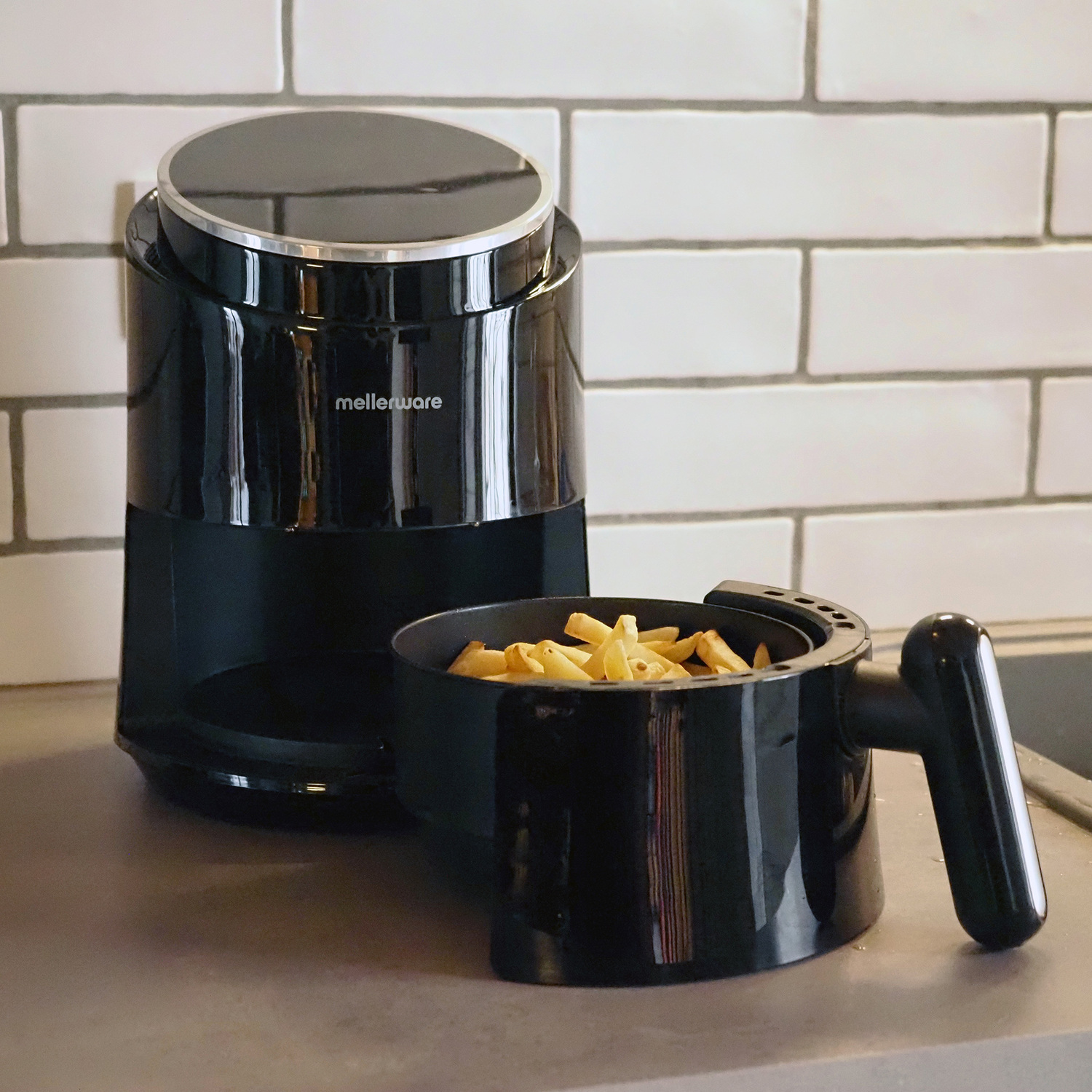 Friggitrice ad aria nera con patatine nel cestello, su un bancone cucina.