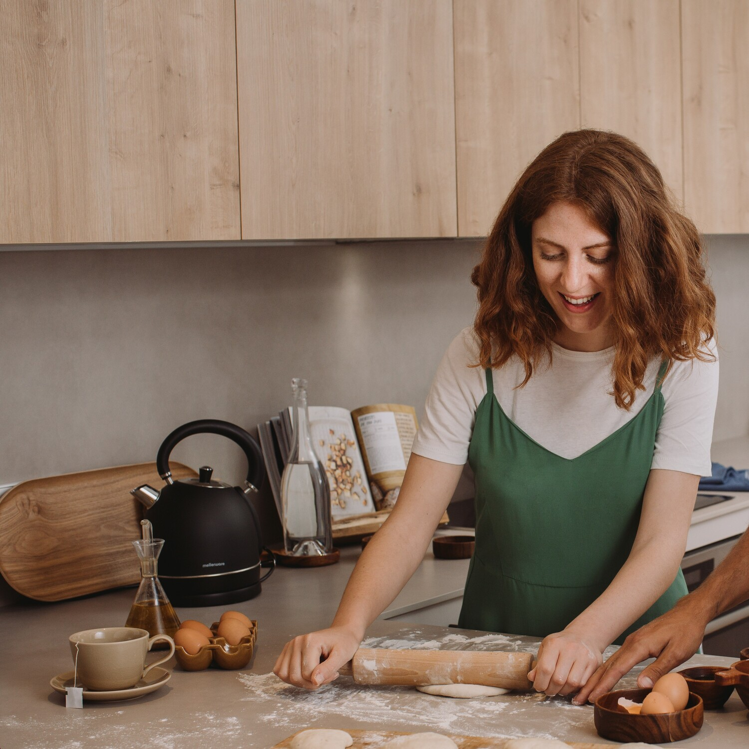 Mujer amasando masa en una cocina con varios utensilios de cocina.