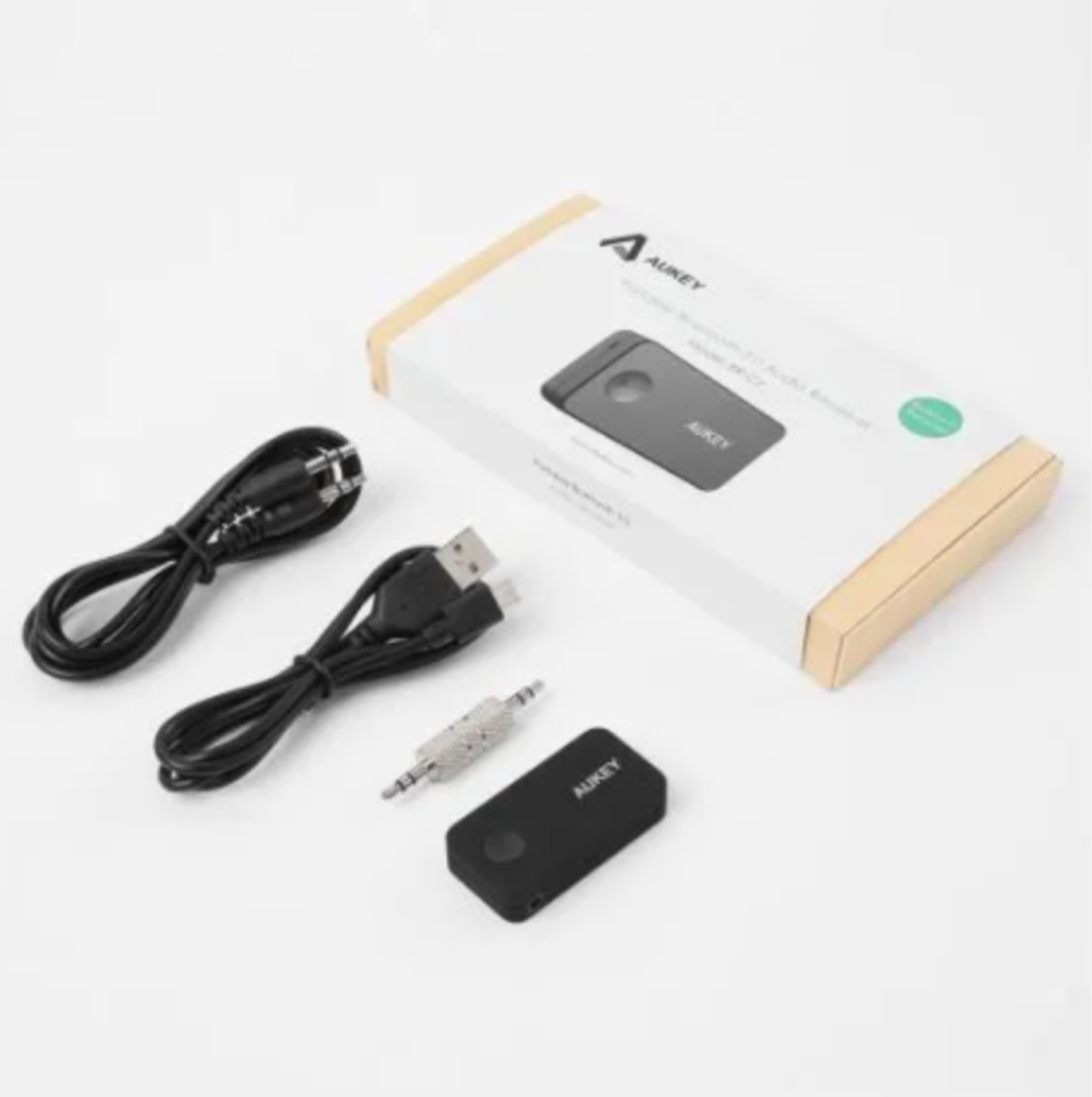 Schwarzes Aukey-Gerät, Kabel und eine Box mit dem Bild des Geräts auf weißer Oberfläche.