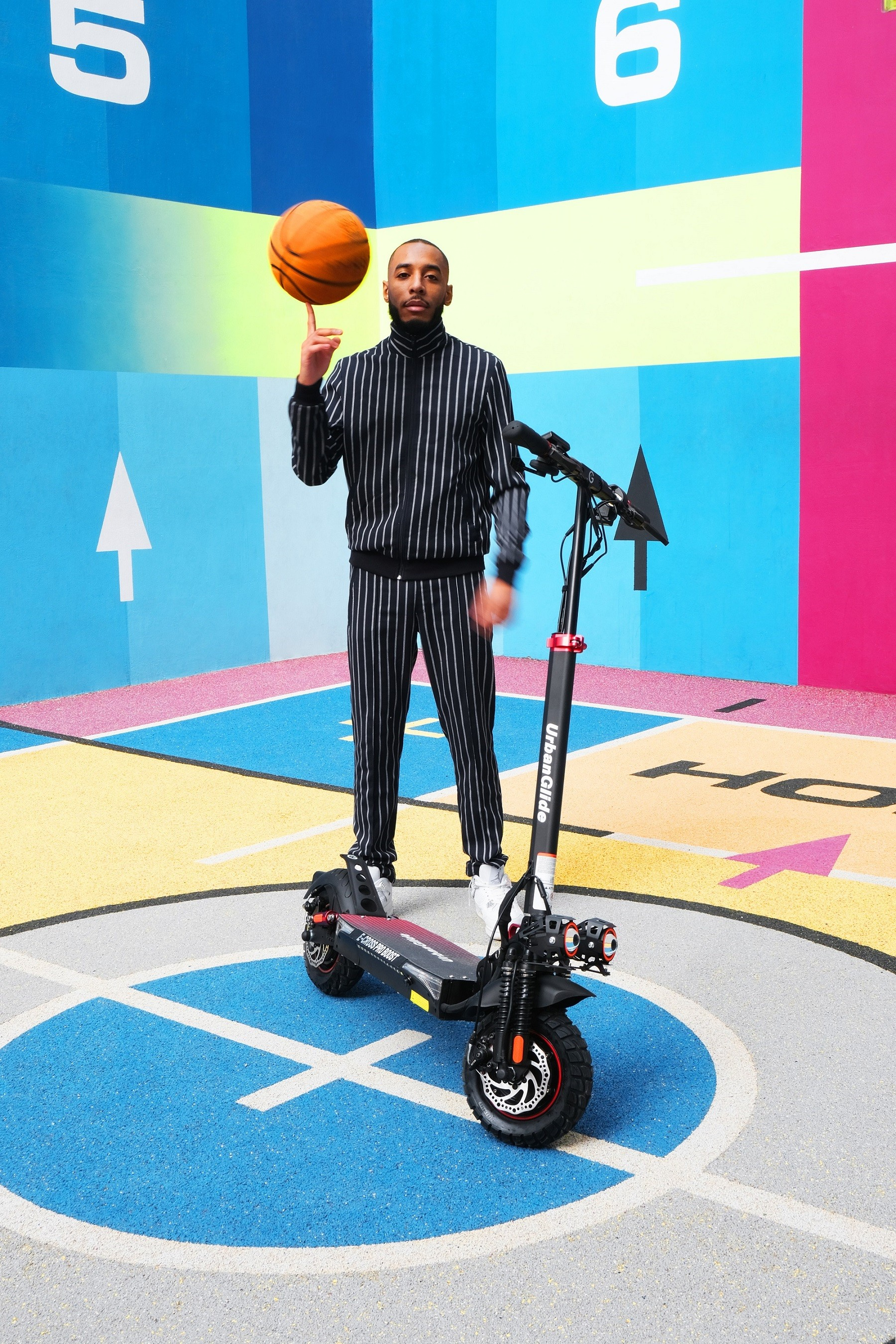 Hombre equilibra un baloncesto en el dedo, de pie sobre un scooter. Fondo colorido con flechas y patrones.