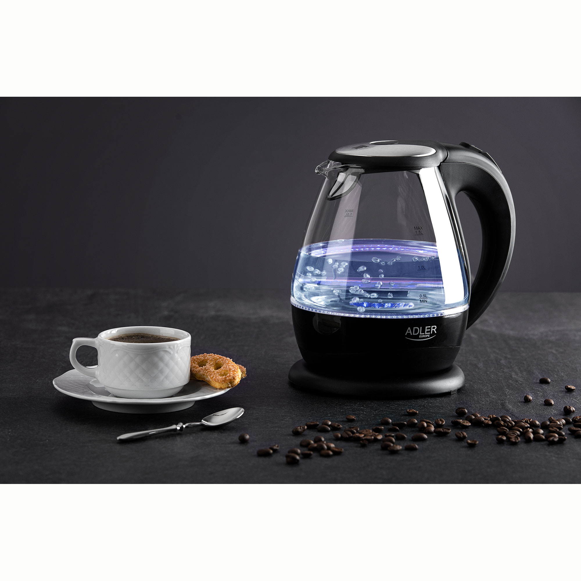 Ein klarer elektrischer Glaskessel mit blauen Lichtern, eine Tasse Kaffee und Bohnen.