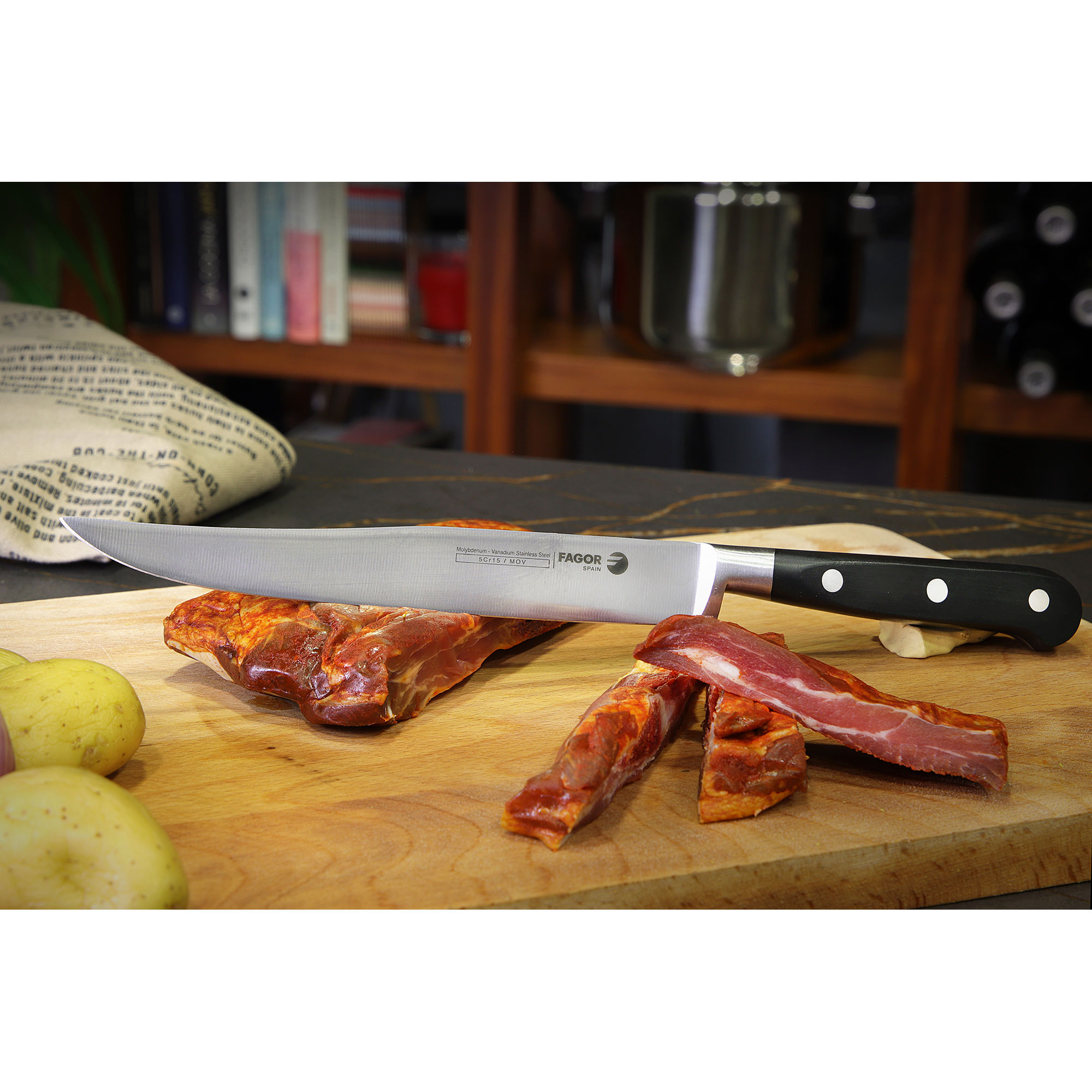 Cuchillo en tabla de cortar con comida. Patatas delante, estanterías de madera al fondo.
