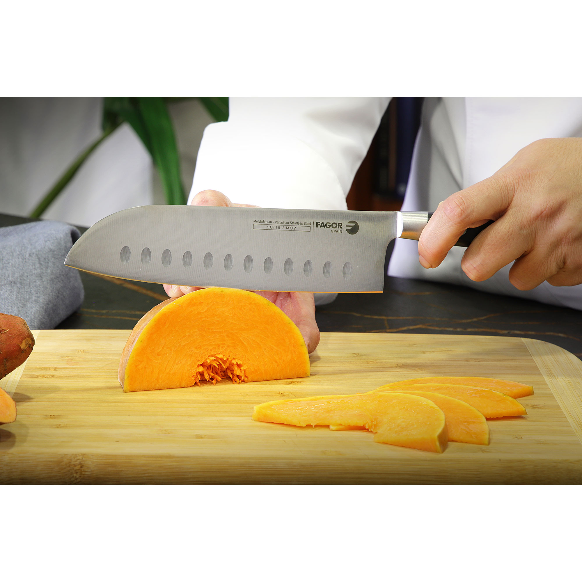 Un chef cortando calabaza con un cuchillo grande en una tabla de cortar de madera.