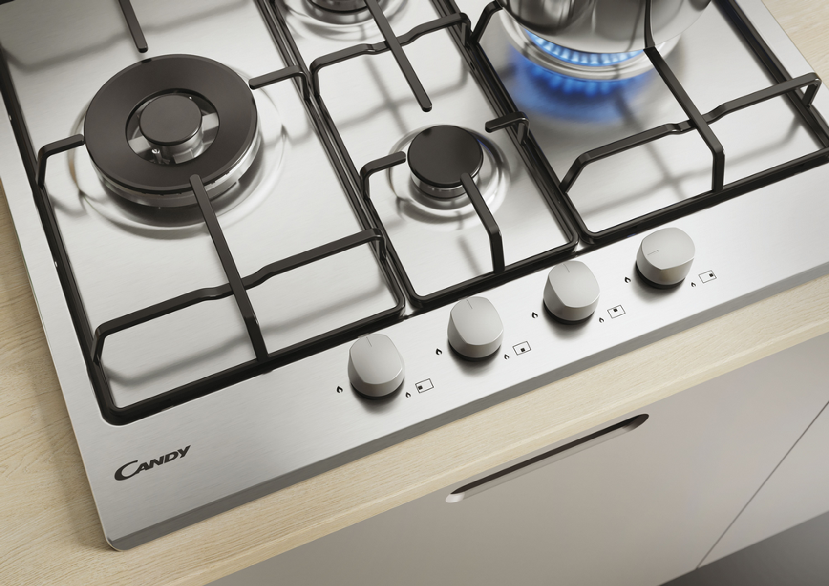 Gazowa płyta kuchenna ze stali nierdzewnej z czterema palnikami i pokrętłami, na jasnej powierzchni drewnianej.
