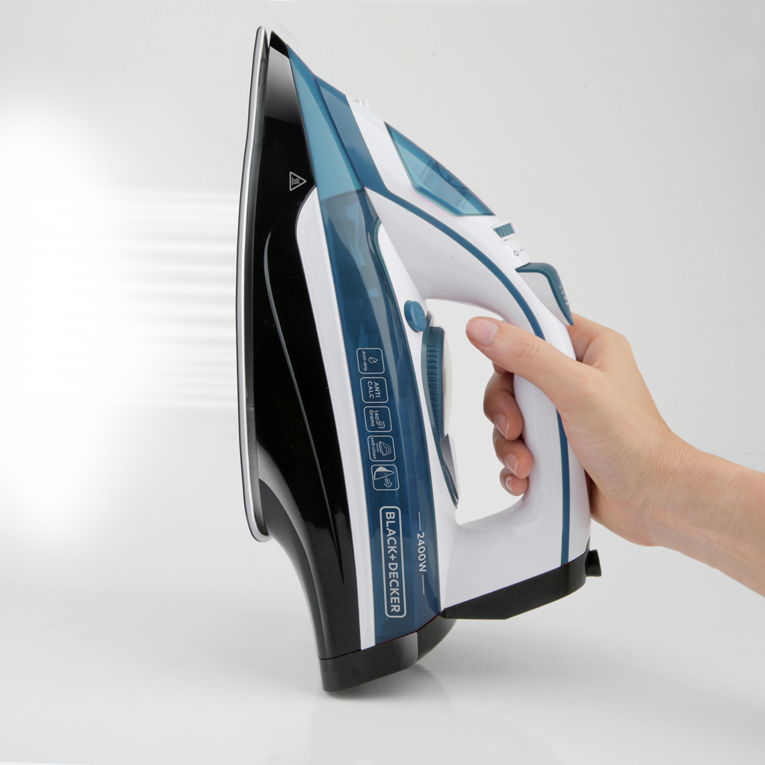 Ręka trzyma czarno-białe żelazko, wydobywa się para. Żelazko na białym tle.