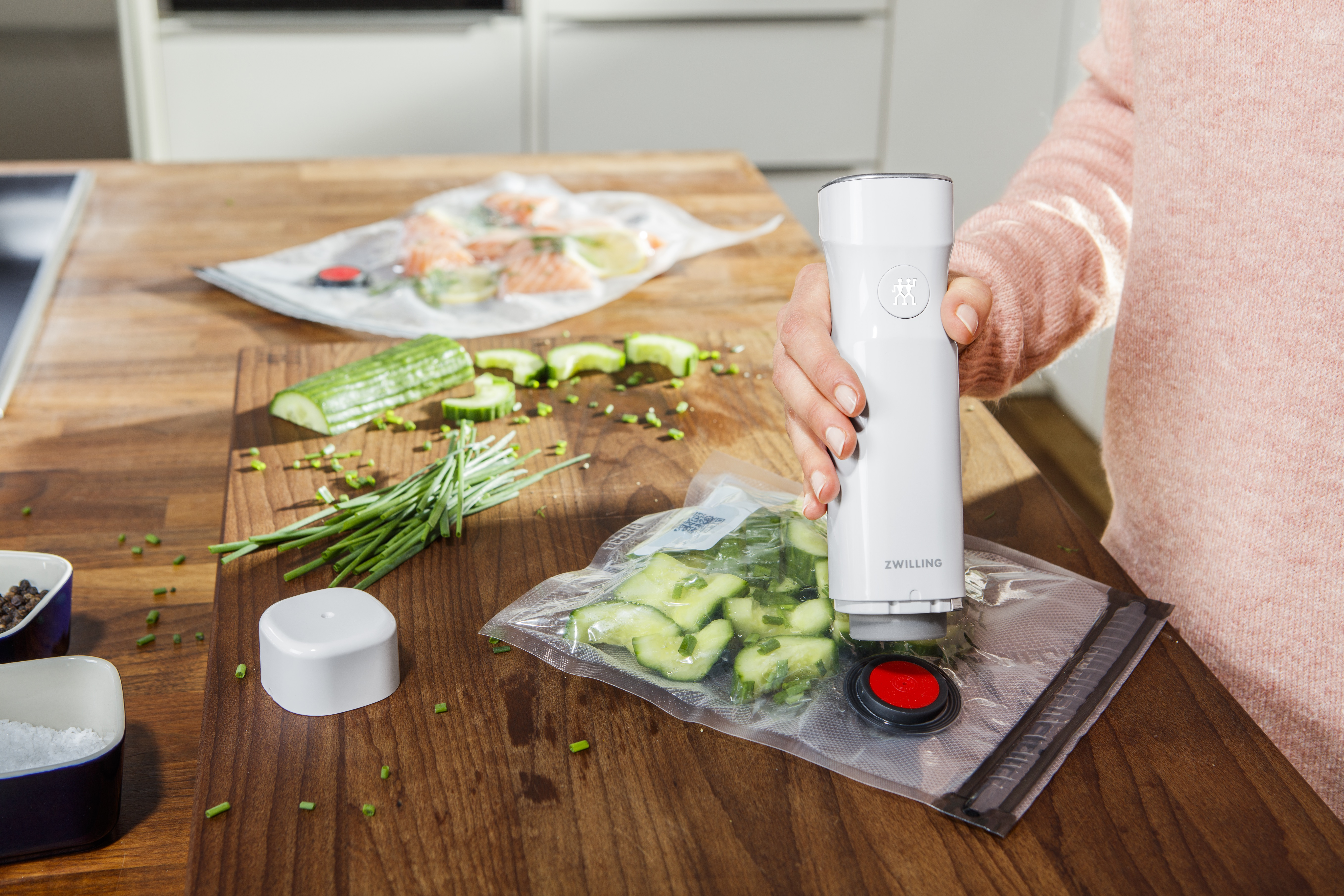 Kobieta używa zgrzewarki próżniowej. Warzywa i owoce w plastikowych workach na stole.