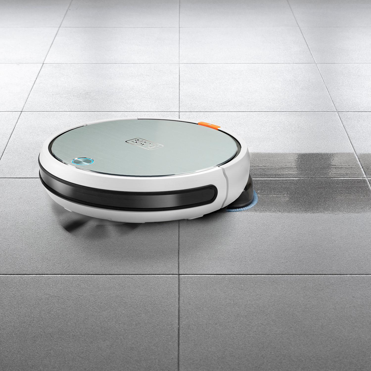 Biało-czarny robot odkurzający na szarej podłodze z płytek, sprzątający.