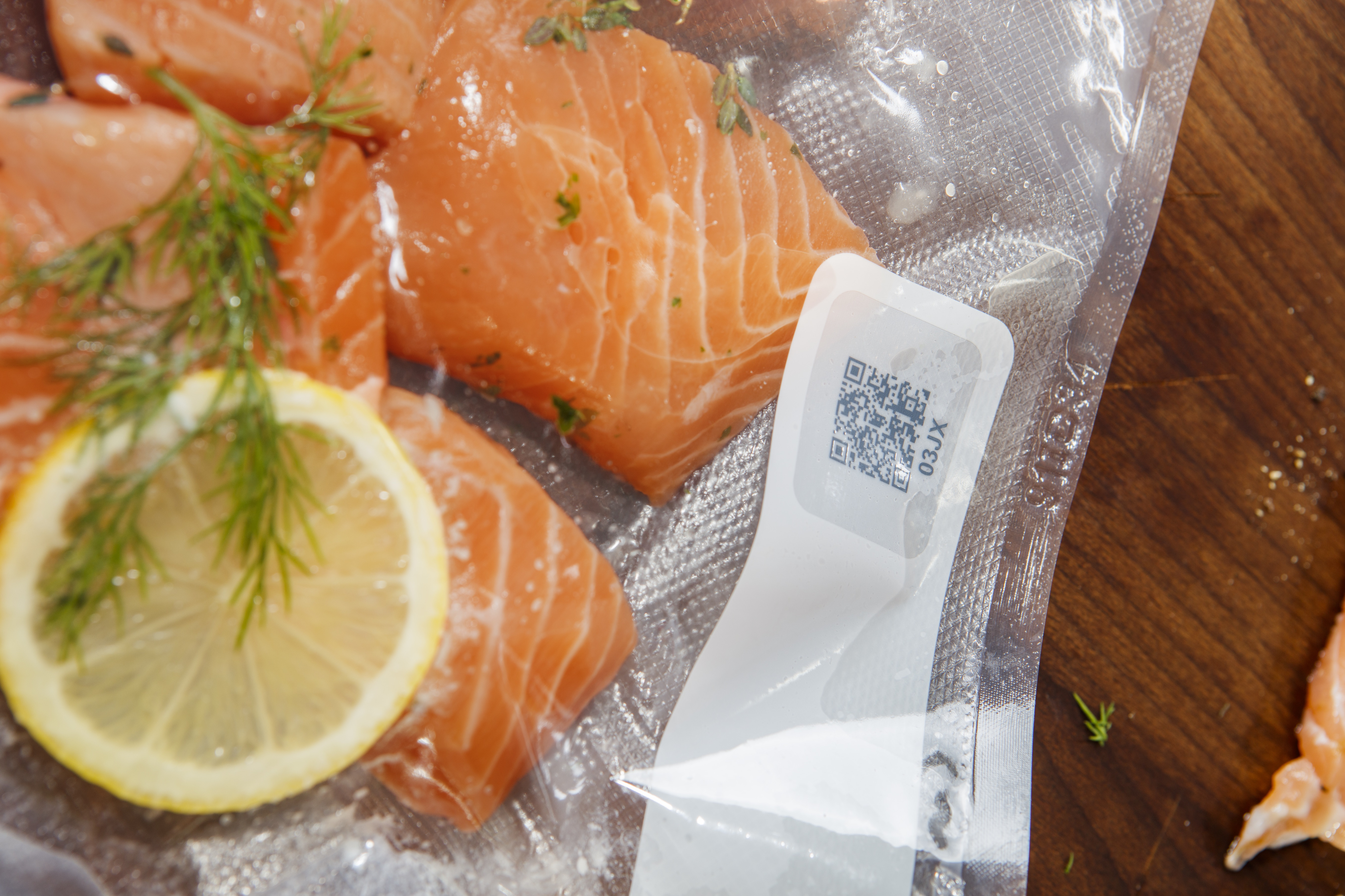 Filetes de salmón en una bolsa de plástico. Una rodaja de limón y eneldo están junto al salmón.
