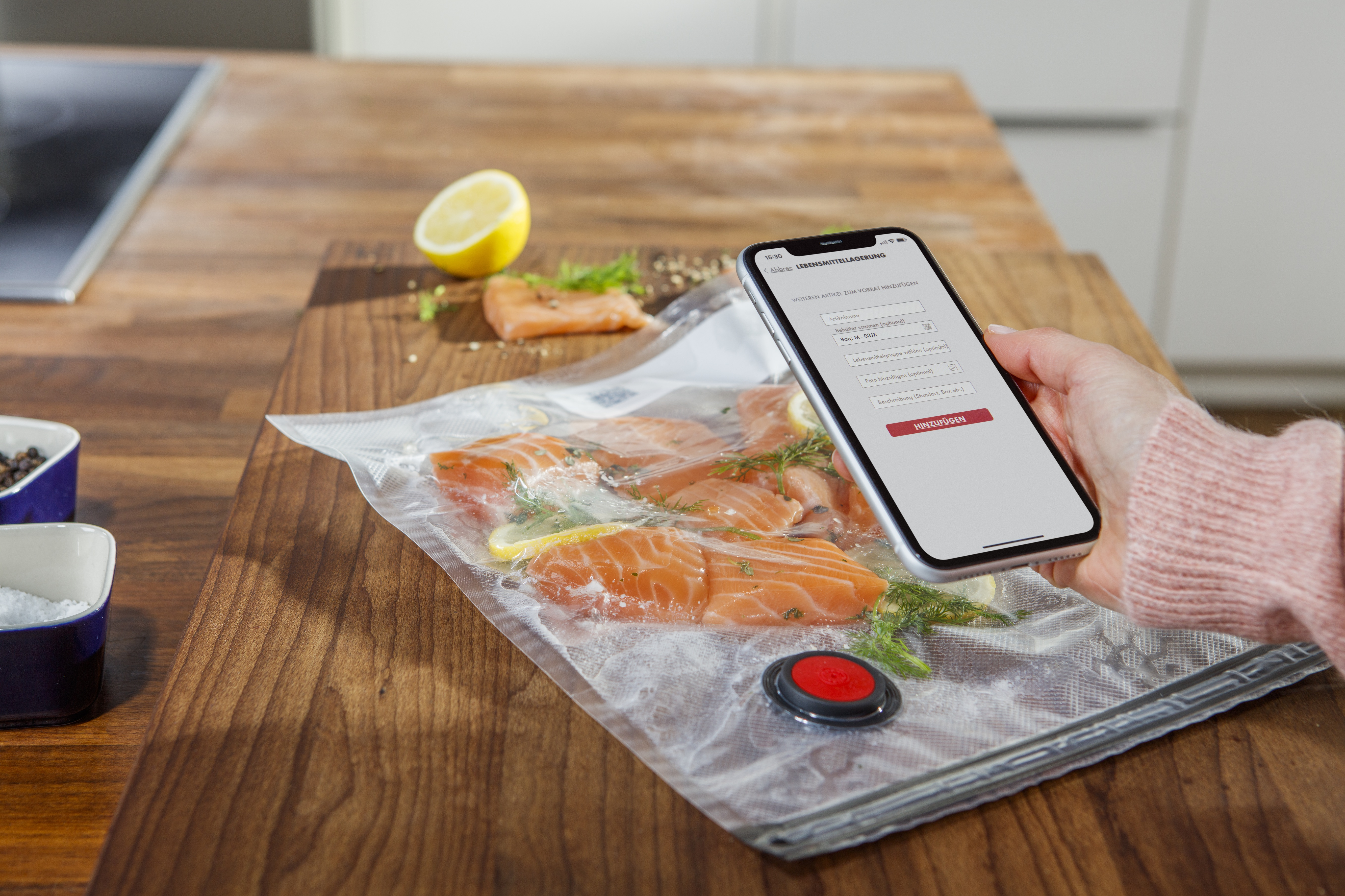 Una persona escanea con un smartphone un paquete de filetes de salmón sellados al vacío sobre una superficie de madera.