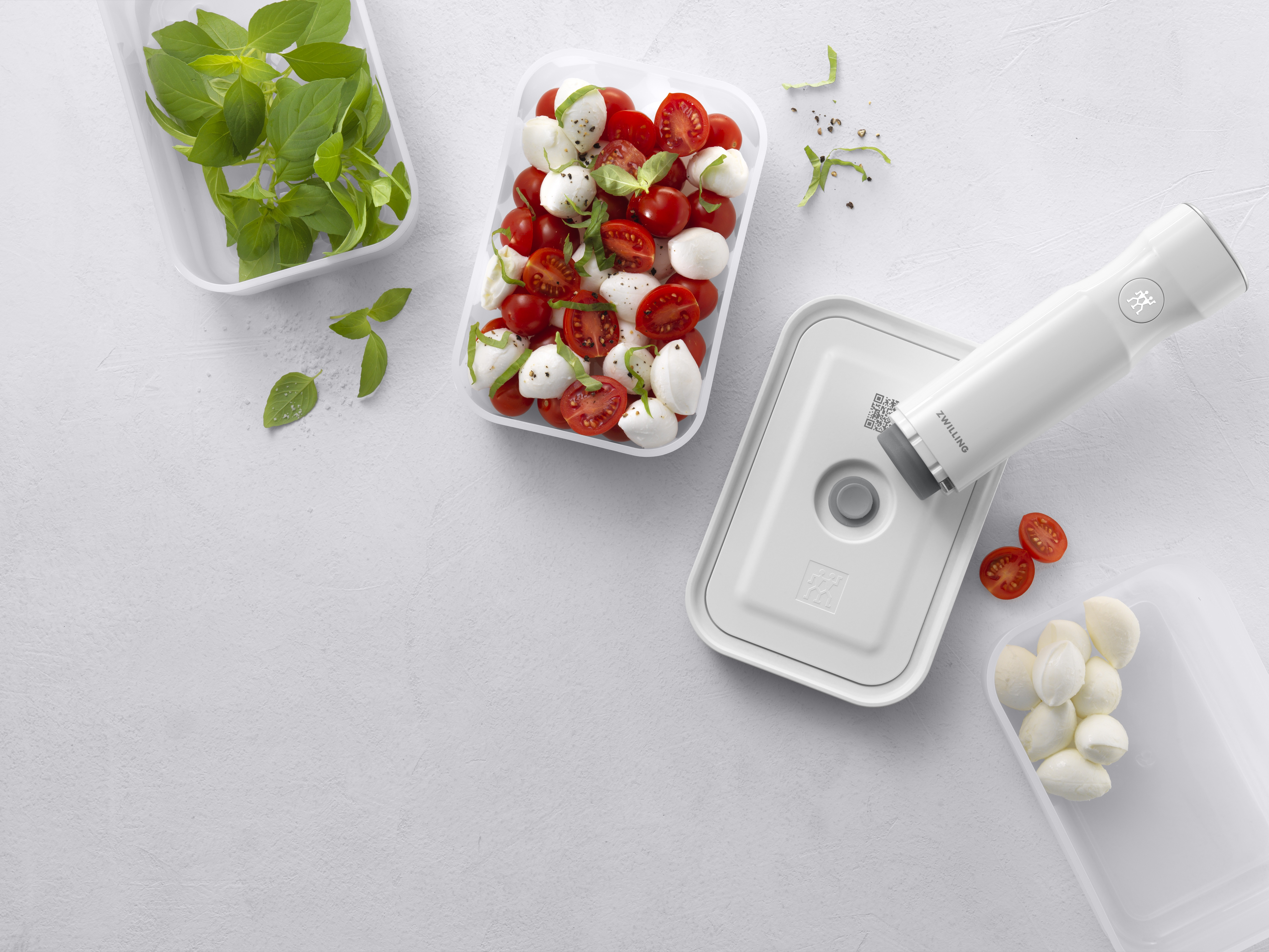 Ingredientes: albahaca, bolas de mozzarella y tomates cherry en recipientes. También hay un sellador al vacío.