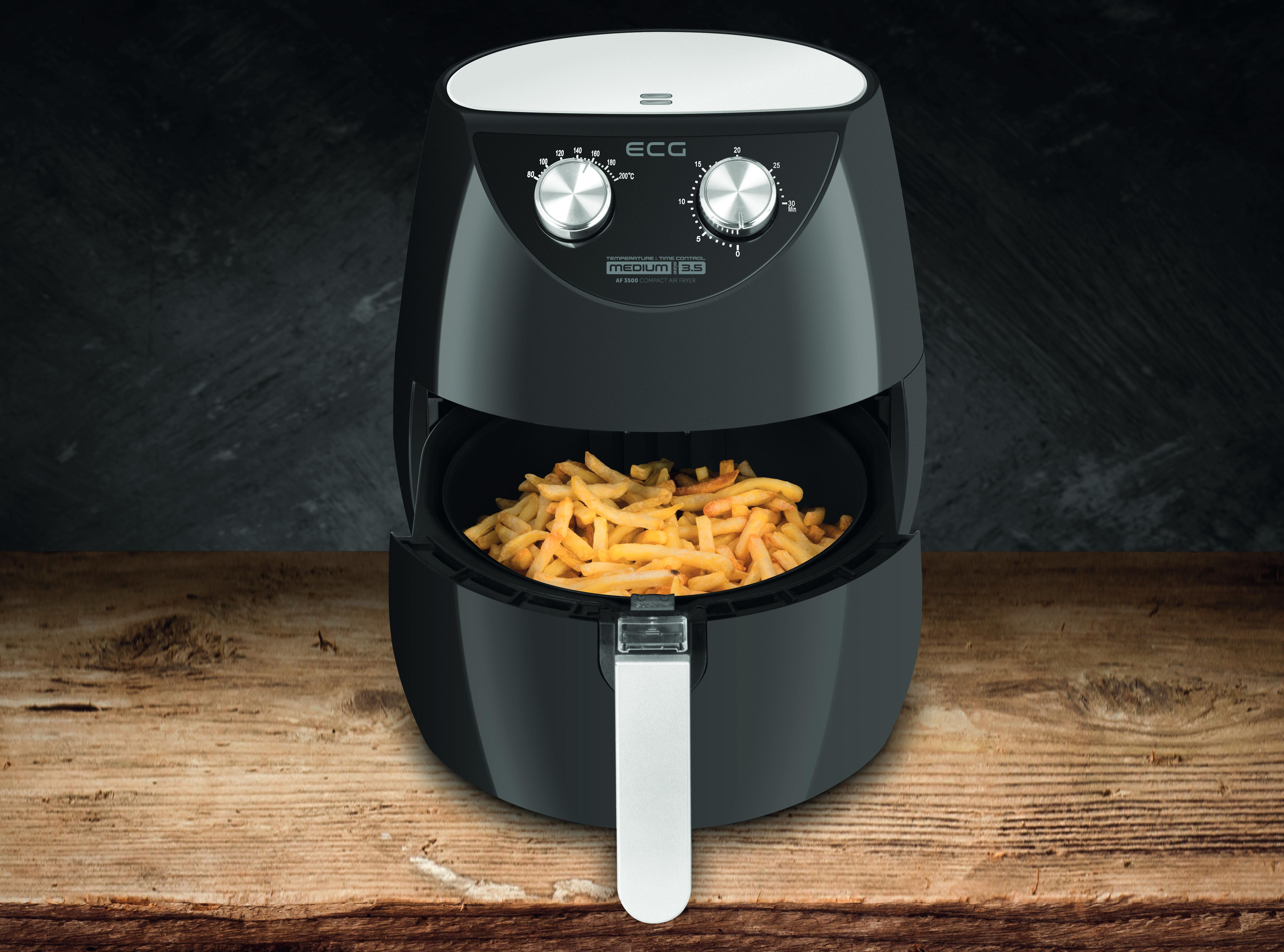 Czarna frytkownica powietrzna z frytkami w środku, umieszczona na drewnianej powierzchni.