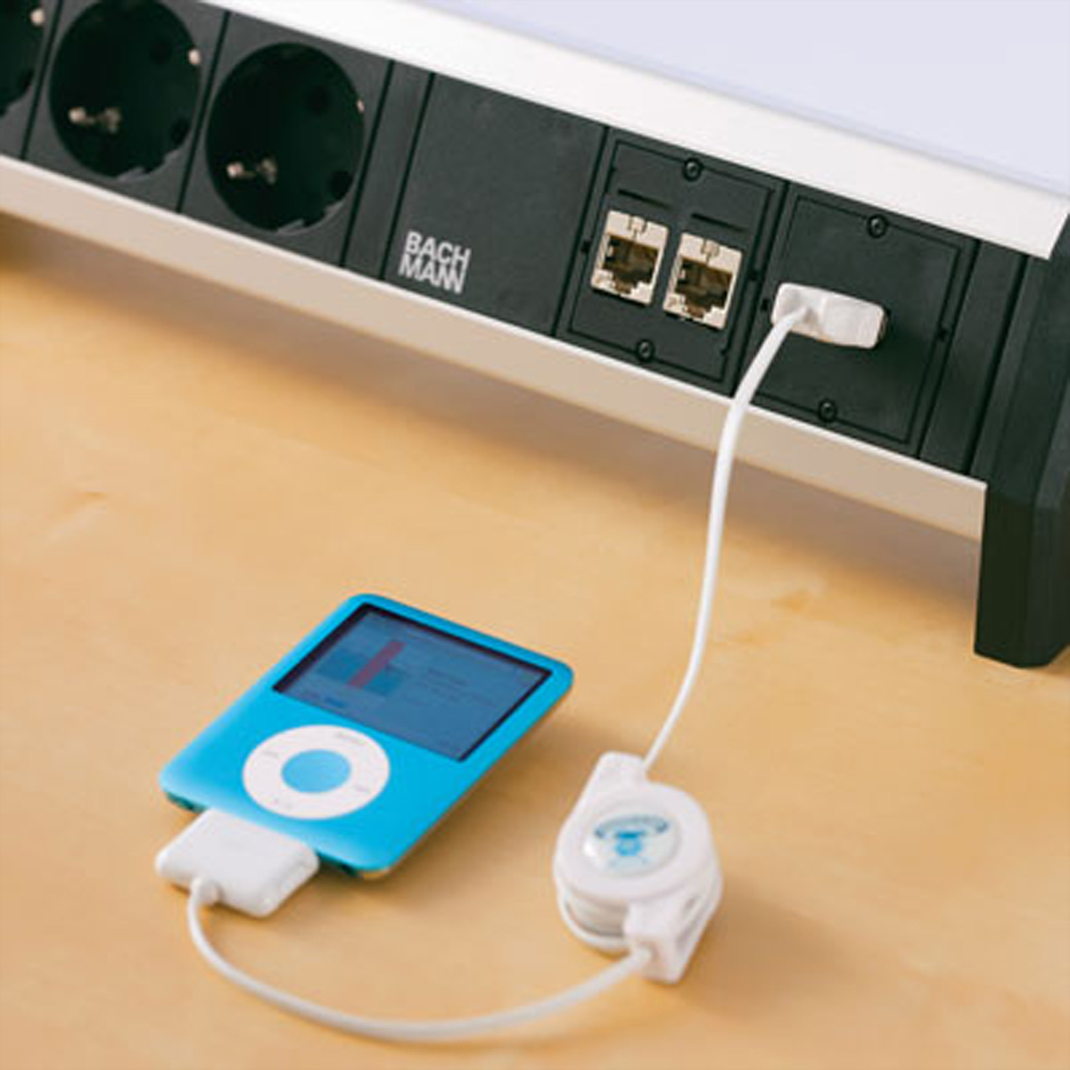 Niebieski iPod podłączony do listwy zasilającej, z chowanym białym kablem i innymi portami.