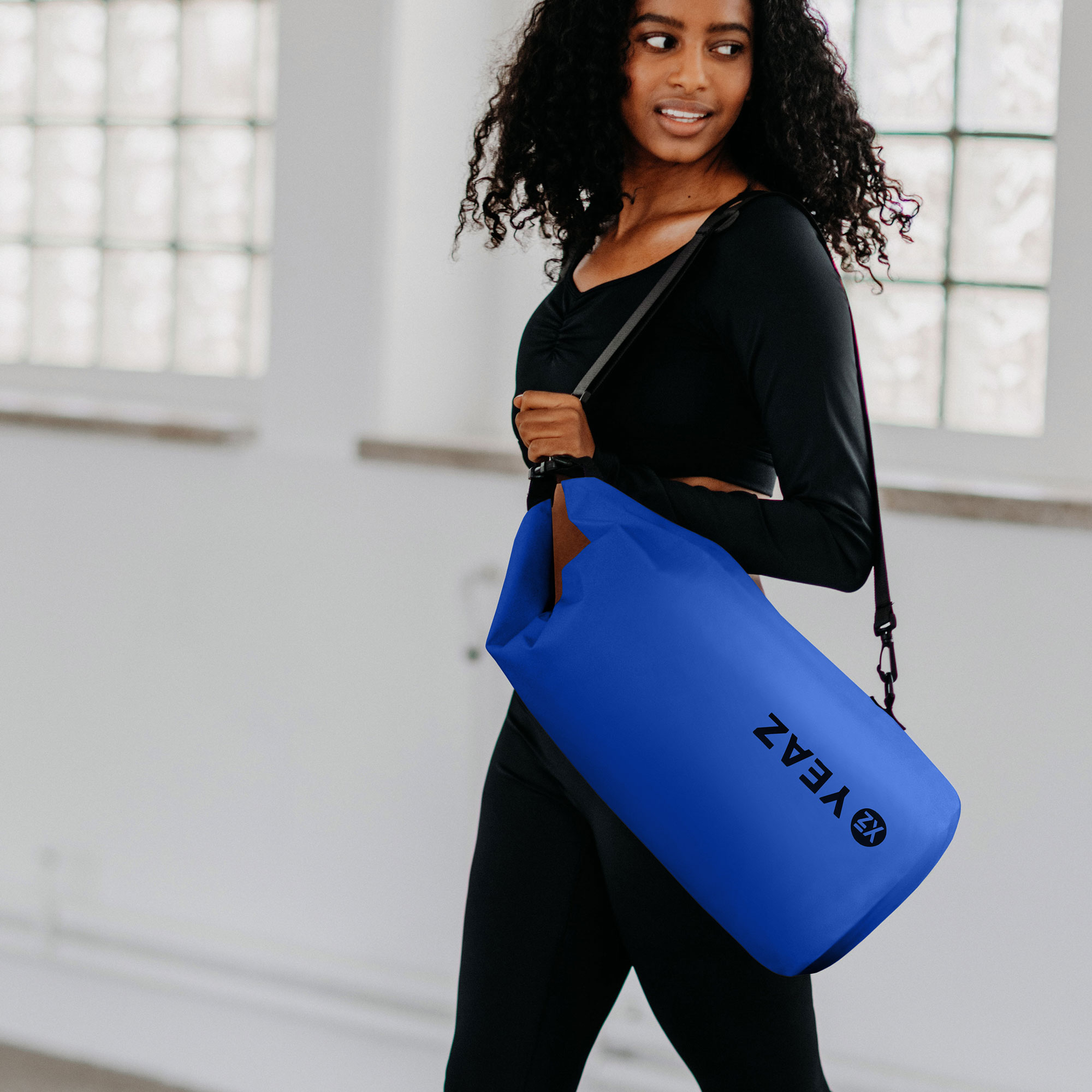 Mujer sosteniendo una bolsa cilíndrica azul con la palabra VEAZ.