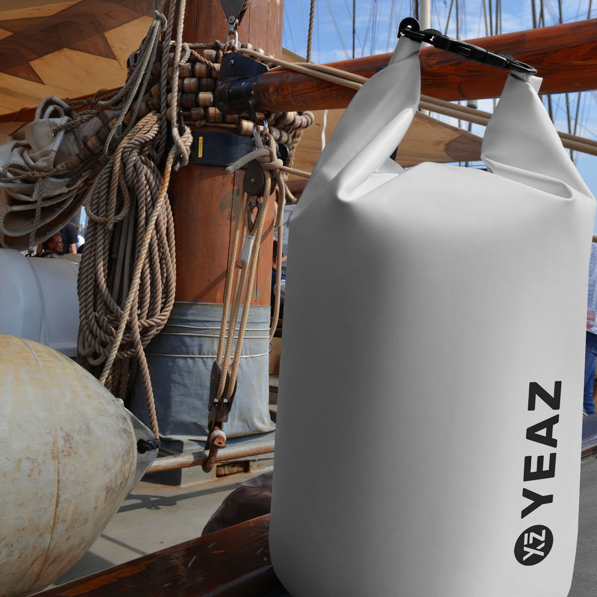 Una bolsa blanca e impermeable en un barco, con cuerdas y un mástil de madera al fondo.