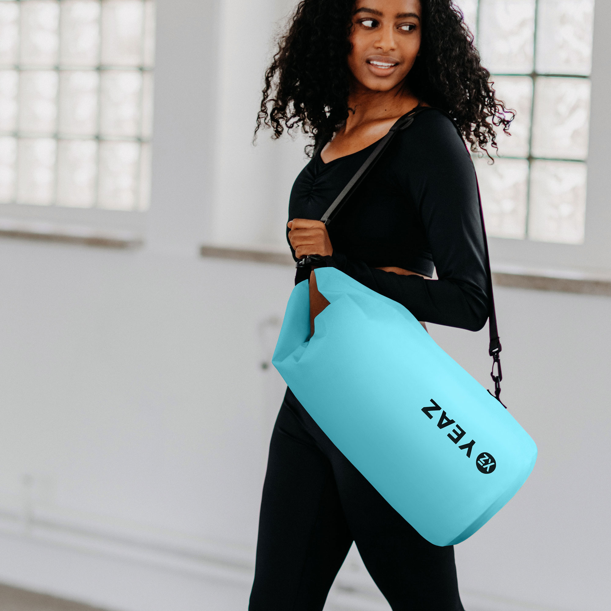 Mujer que lleva una bolsa cilíndrica azul.