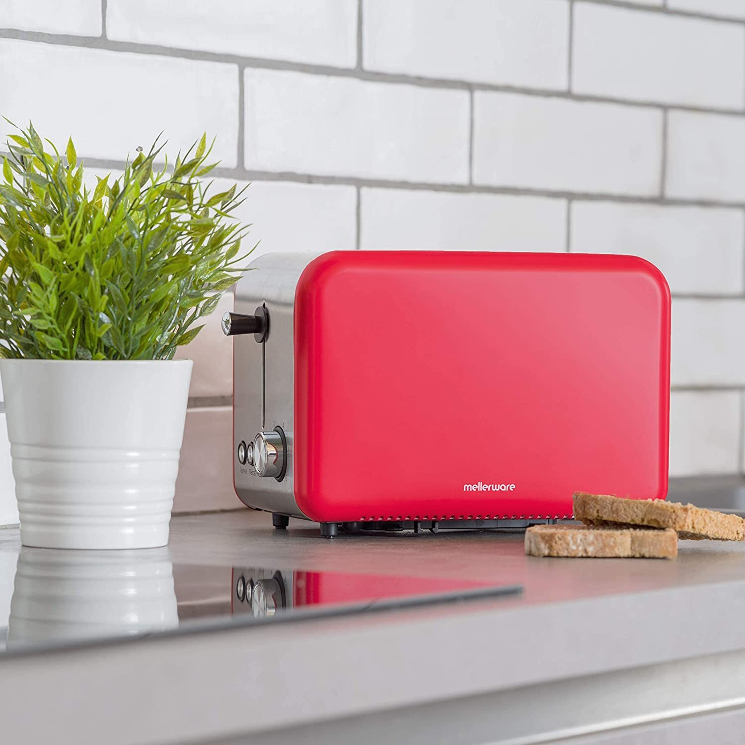 Una tostadora roja retro con dos rebanadas de pan tostado en una encimera junto a una planta.