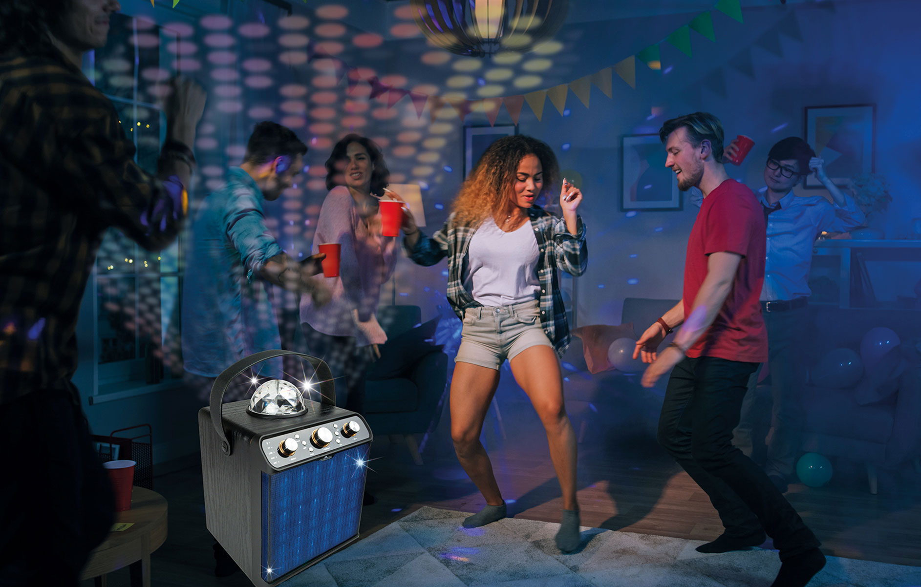 Gruppe tanzt in einem Raum mit Discokugel, Jukebox und Partybeleuchtung.